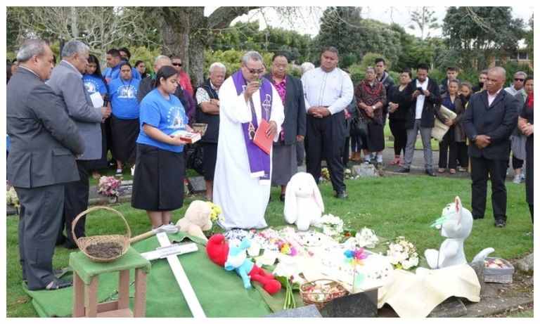 ​A priest blesses the grave of the baby who was found abandoned in a reserve in Māngere. Photo/RNZ/ Sally Murphy​