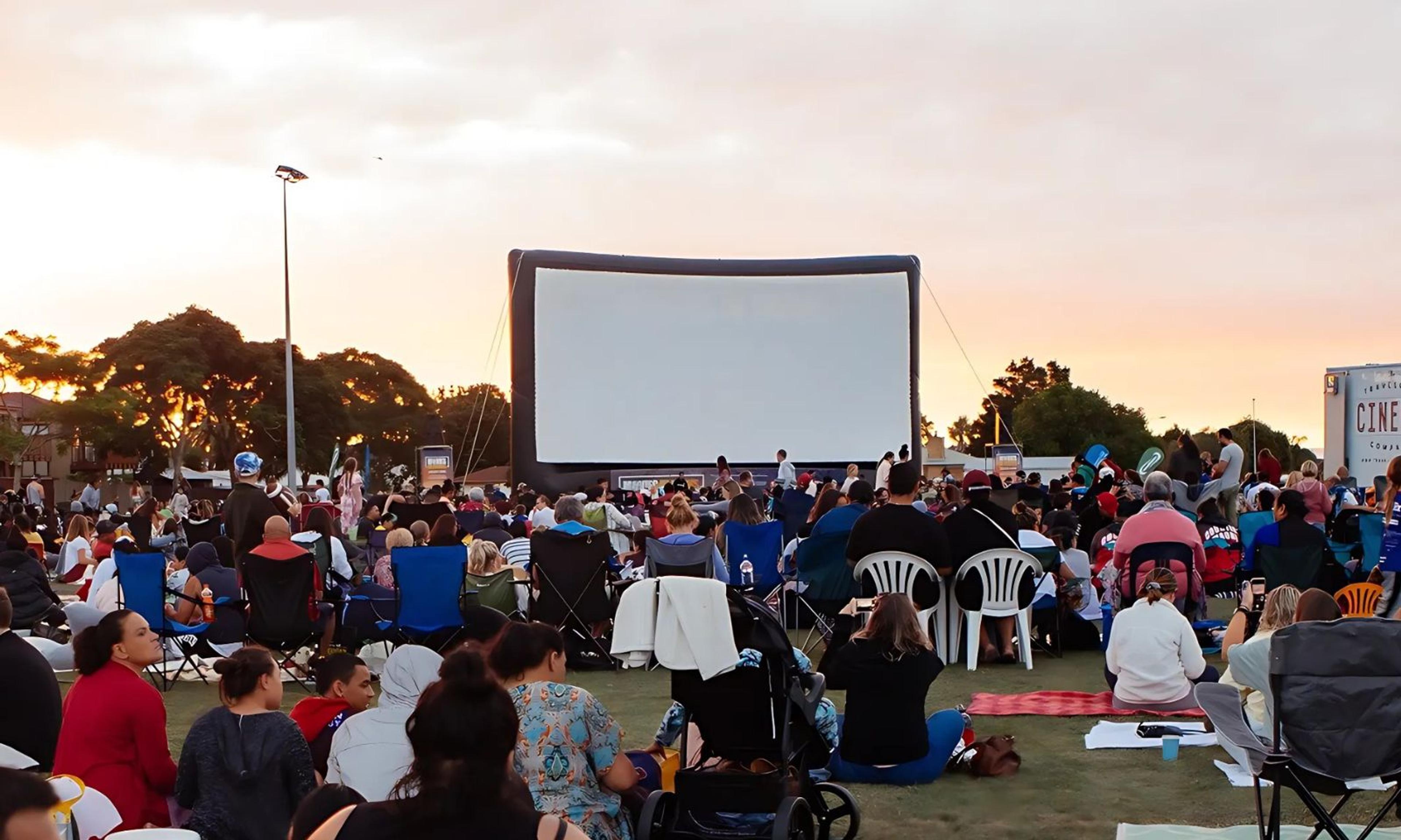 A group of friends laughing and enjoying themselves at a pop-up outdoor movie screening in Auckland.