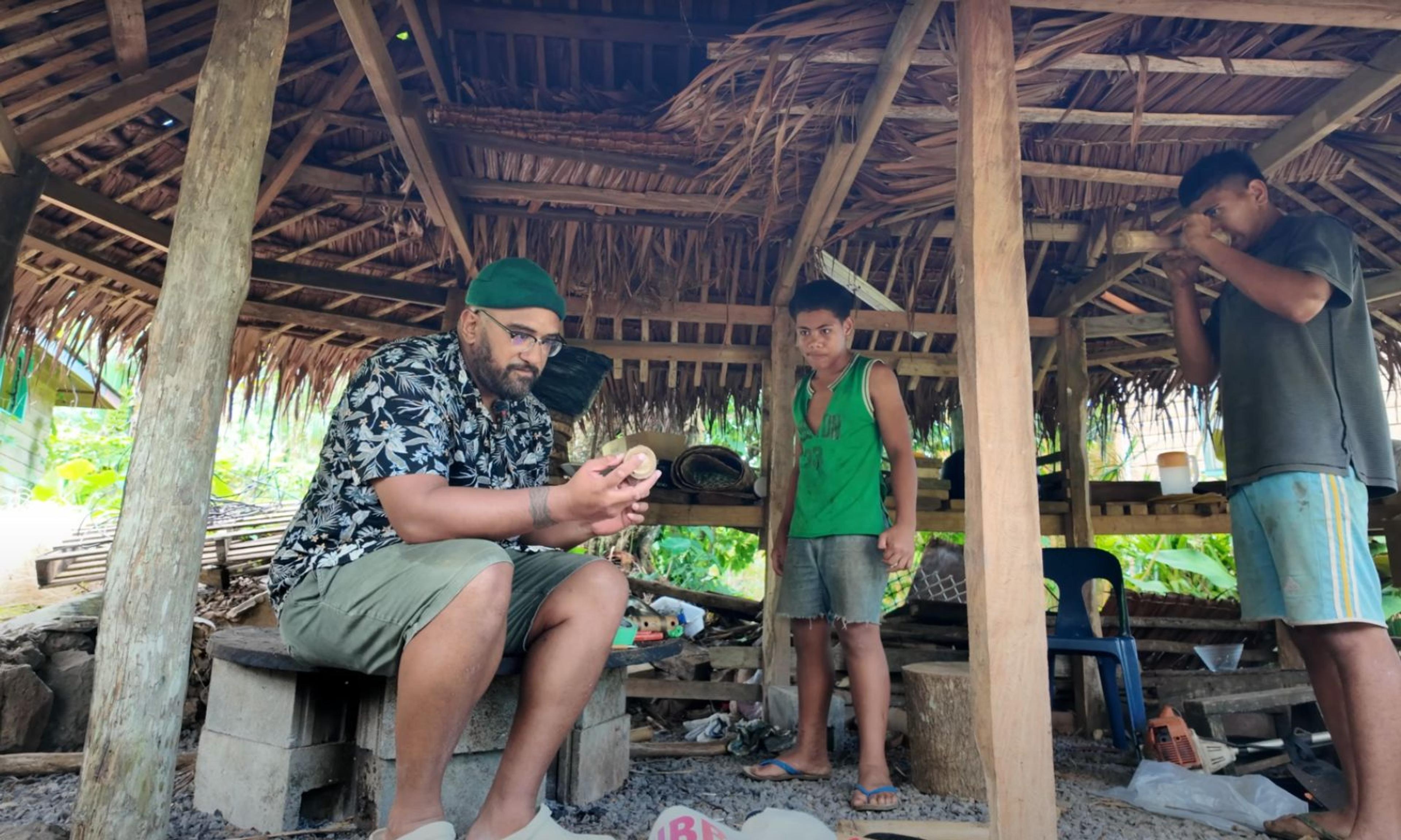 Saia Tu'itahi teaching two young boys in Sāmoa to make and play their own fangufangu (nose flute).