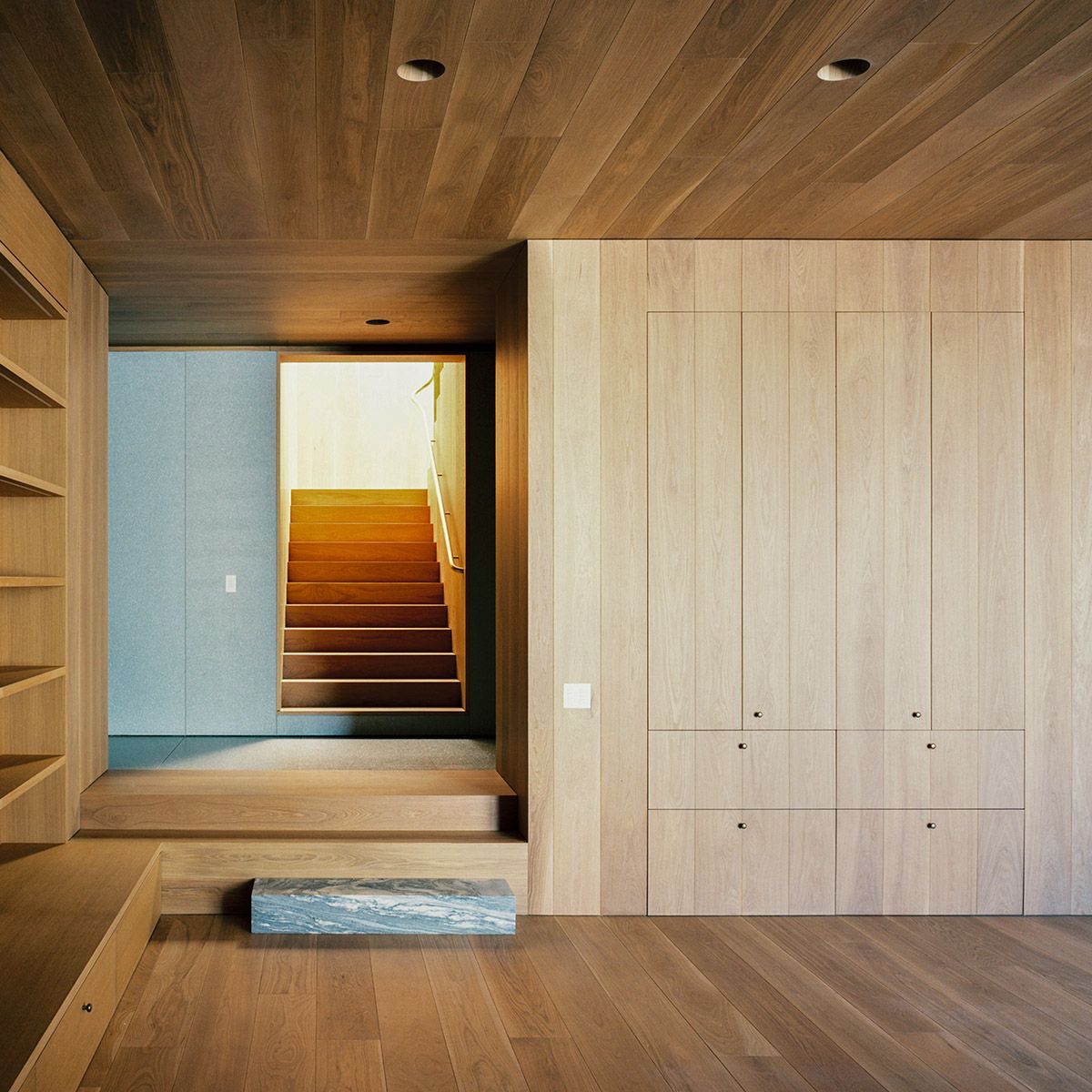 Small recessed downlights integrated into a wood ceiling above custom millwork and a stair landing.