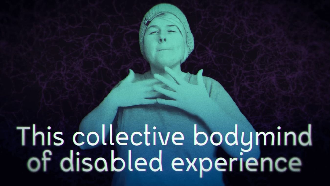 Person wearing a hat with both hands in front of the chest. Everything is blue-greenish tinted and in front of a dark background. Caption reads 'This collective bodymind of disabled experience'
