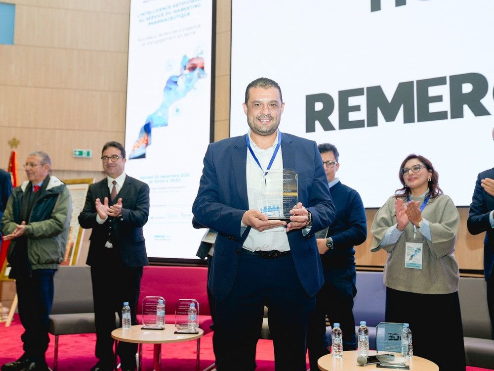 Représentant de Laprophan recevant un trophée sur scène lors de la conférence UM6SS sur l'IA et le marketing pharmaceutique