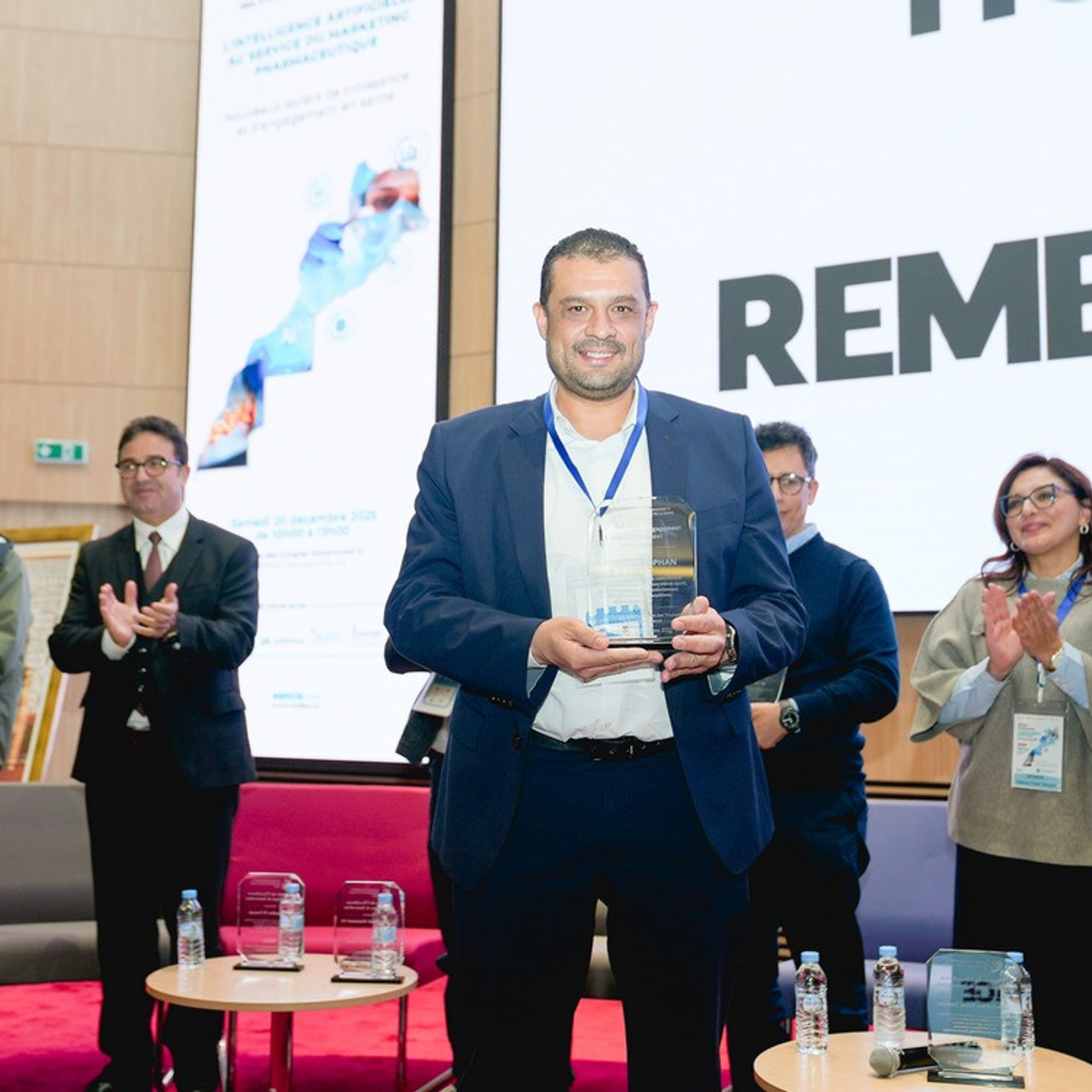 Représentant de Laprophan recevant un trophée sur scène lors de la conférence UM6SS sur l'IA et le marketing pharmaceutique