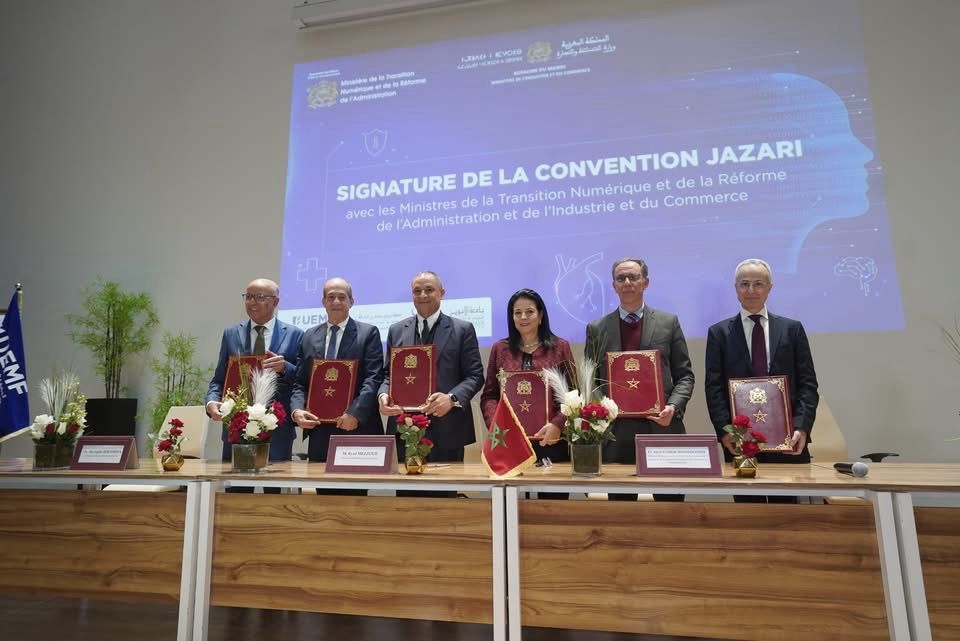 Six officiels posant avec des dossiers rouges lors de la signature de la convention Jazari à l'UEMF