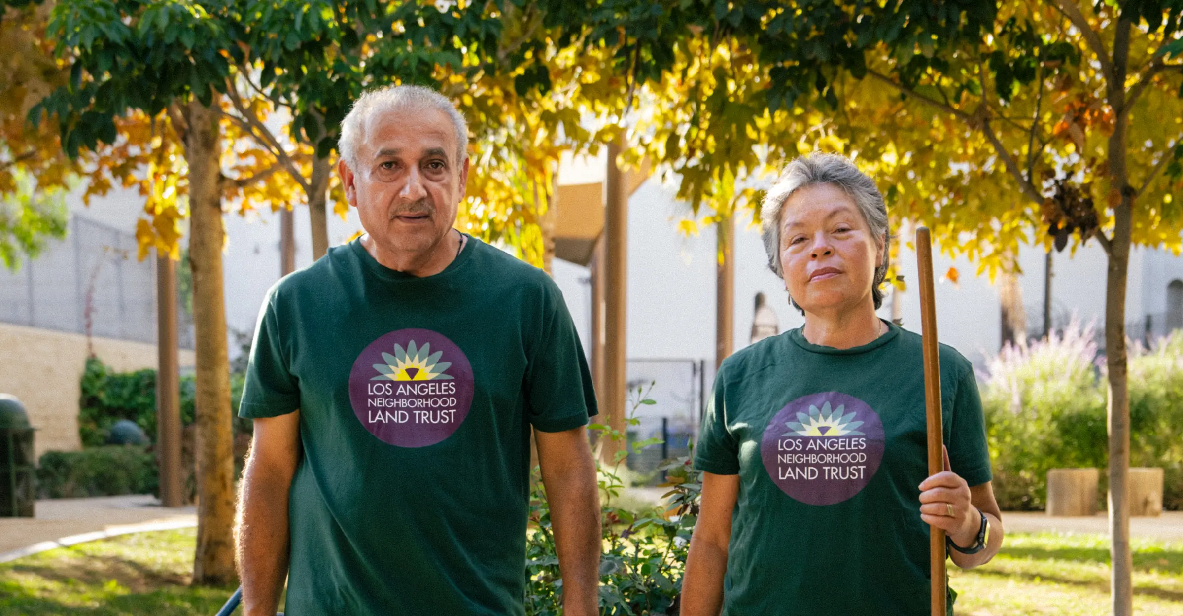 A man and woman stand beside each other wearing LA Neighborhood Land Trust t-shirts