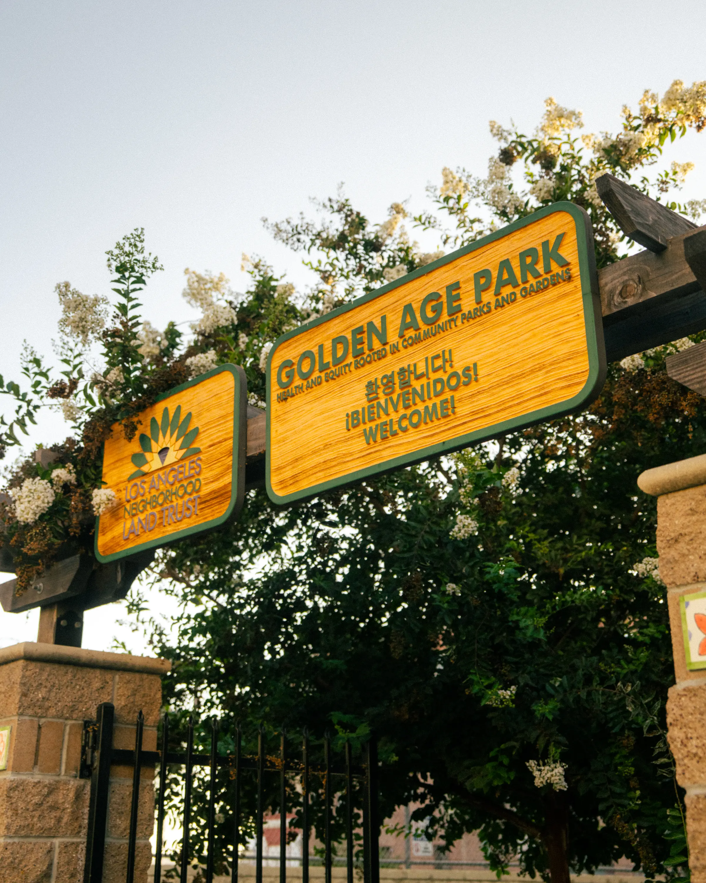 A wooden sign with green writing that reads "Golden Age Park"