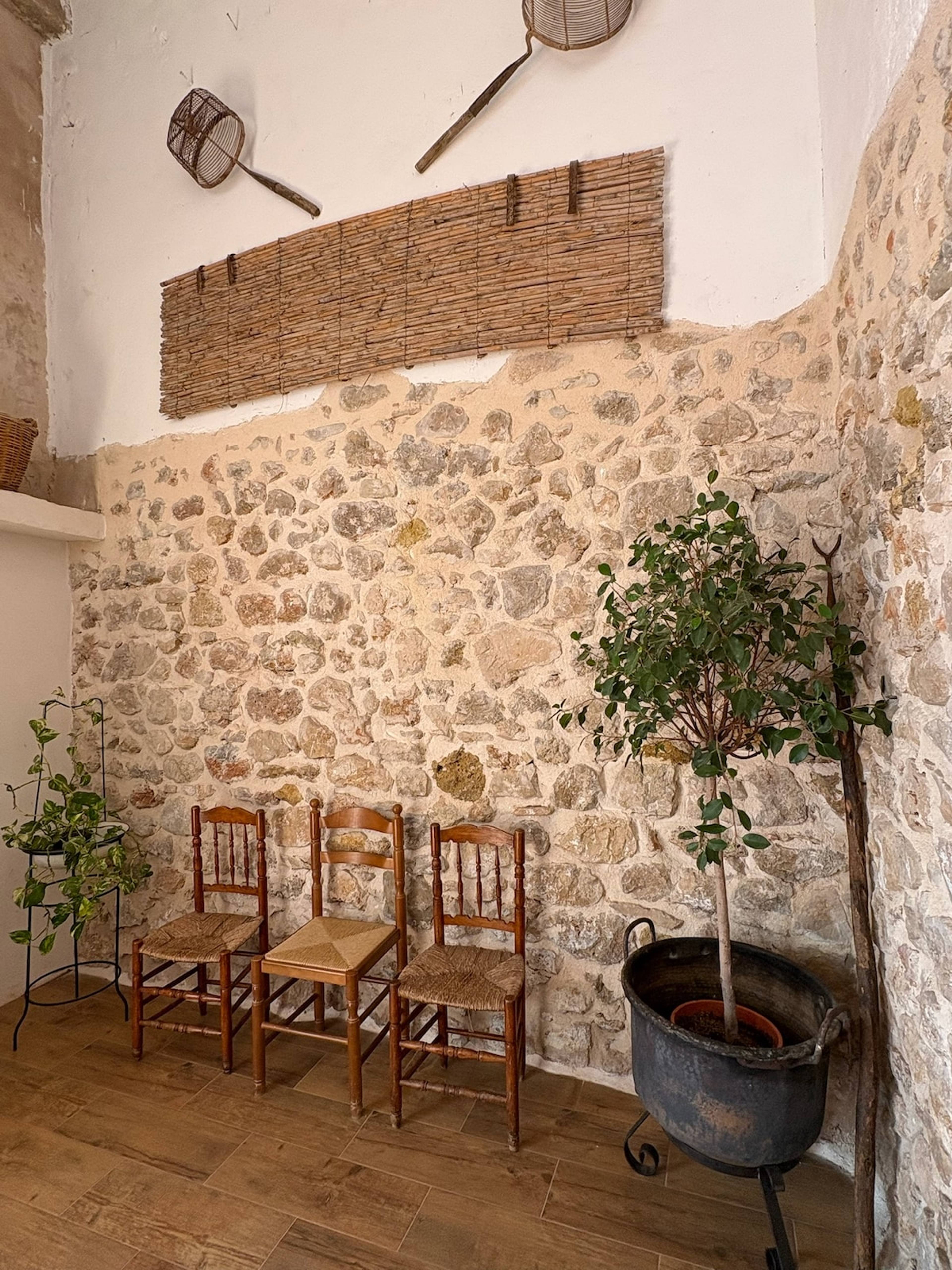 Rincón de terraza con sillón de mimbre junto a la pared de piedra