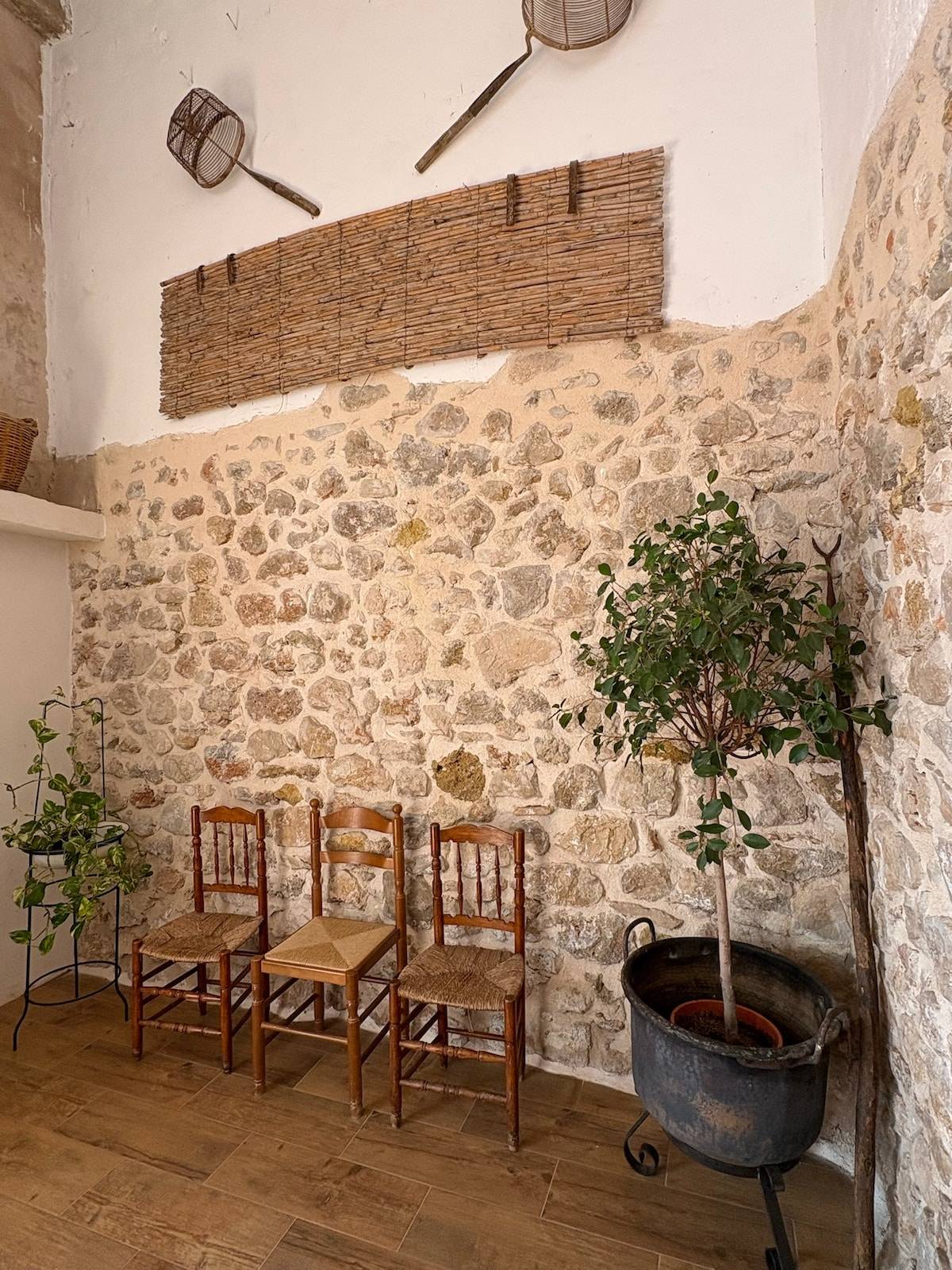 Rincón de terraza con sillón de mimbre junto a la pared de piedra