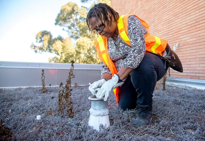 An Enterprise Risk Management employee checks a rooftop vent.