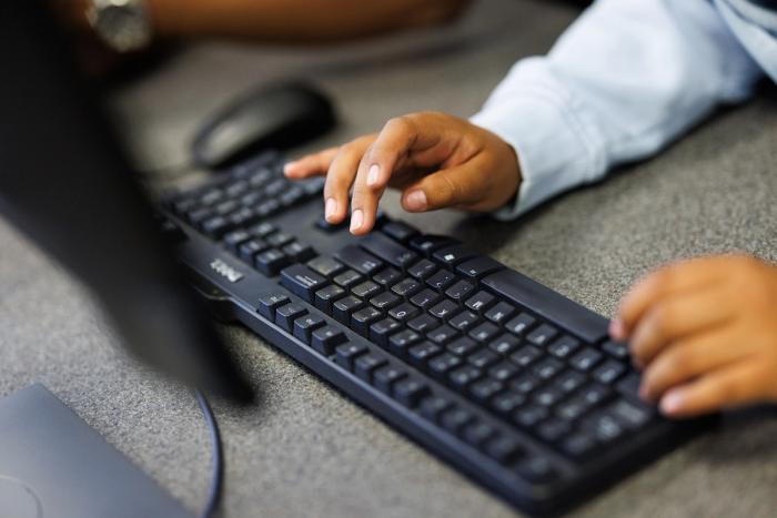 Hands type on a black computer keyboard