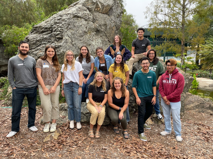 The Cal Poly Green Campus team poses together outside near a rock.