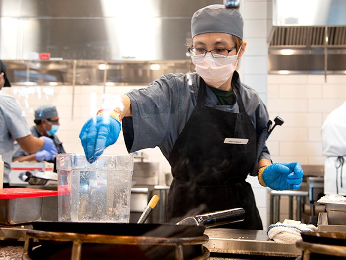 A Campus Dining employee wears a mask and gloves as she prepares food in the new Vista Grande Dining Pavilion at Cal Poly, San Luis Obispo..