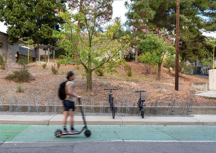 A Cal Poly student rides across campus on an electric scooter. 