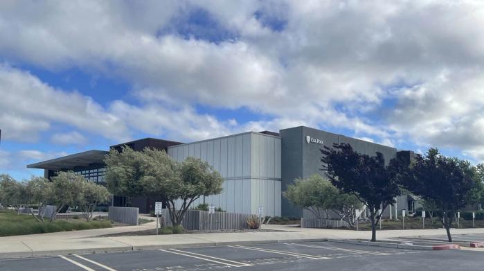 The exterior of Mustang Business Park, surrounded by trees, with a cloudy blue sky.