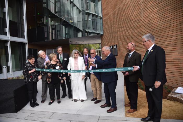 A group of people cut a green Cal Poly ribbon for the opening of the Frost Center.