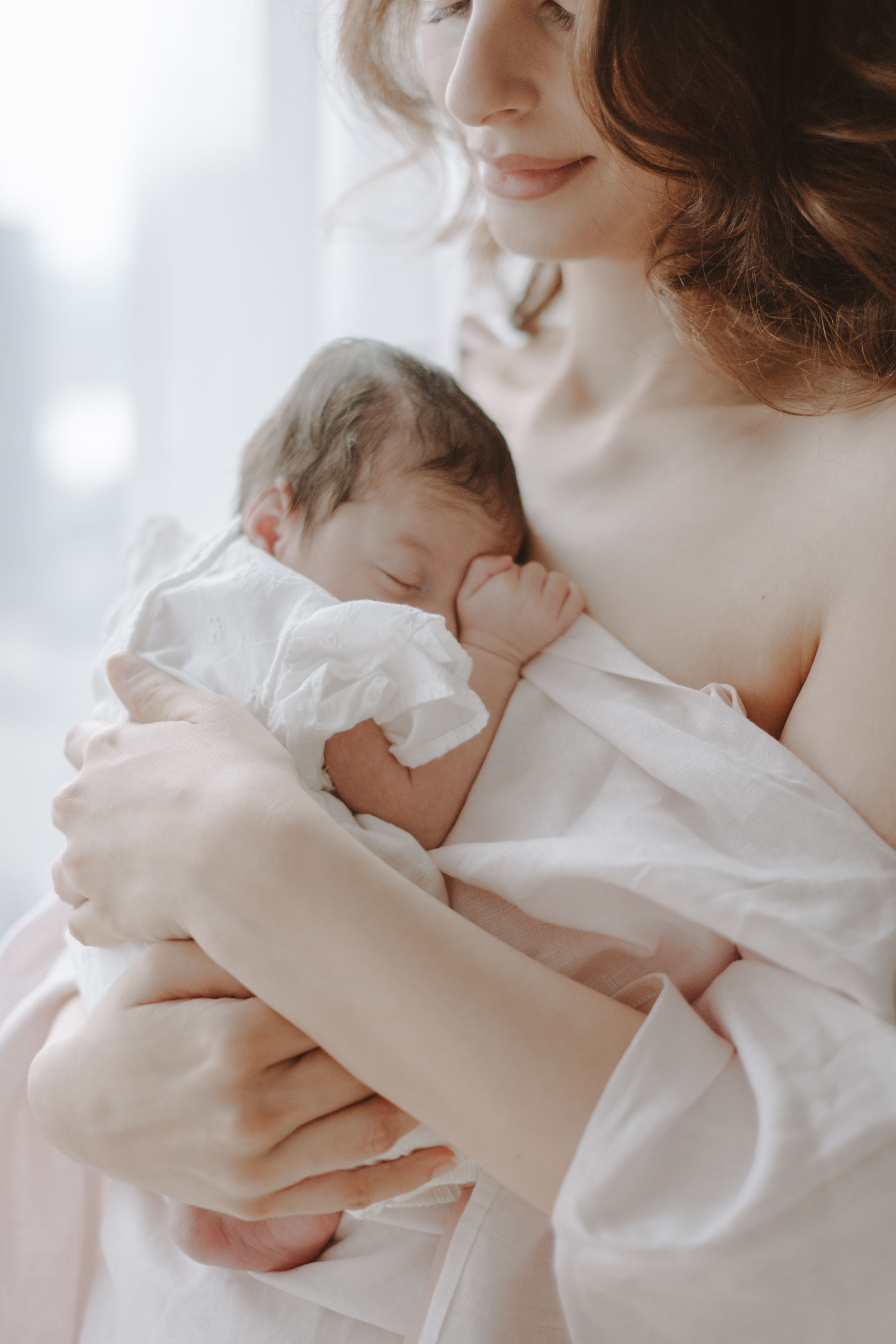 Newborn baby photographed with an older sibling in a bright family home