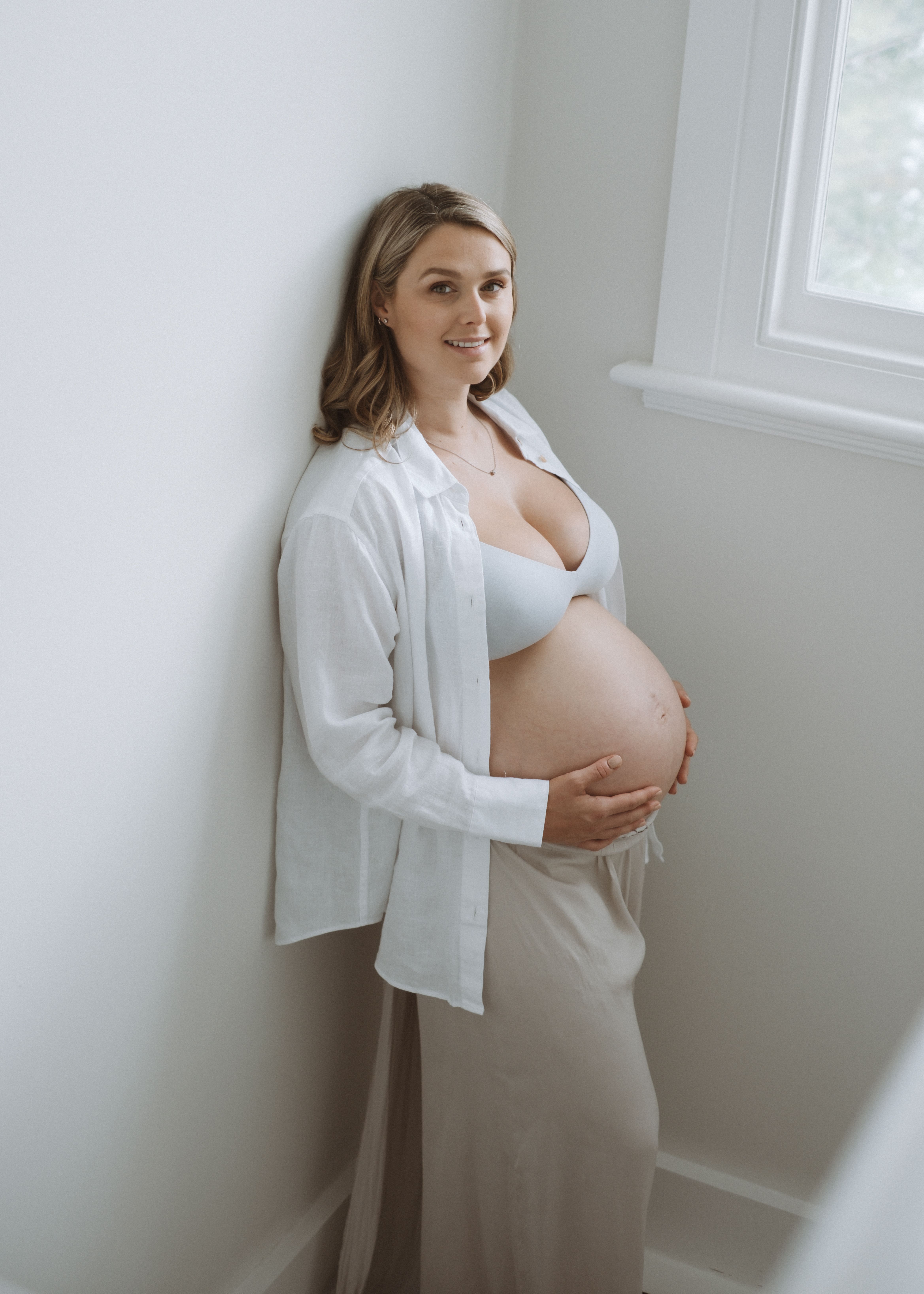Natural seated portrait of an expectant mother in neutral clothing