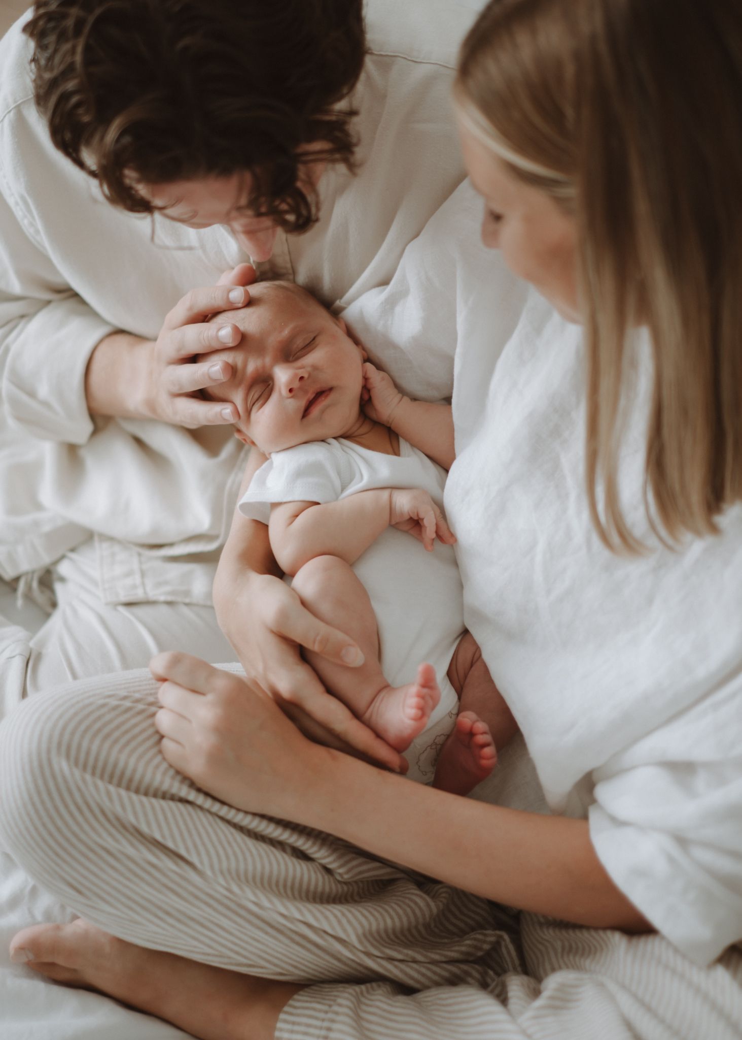 Newborn baby lying comfortably on a bed in soft natural light