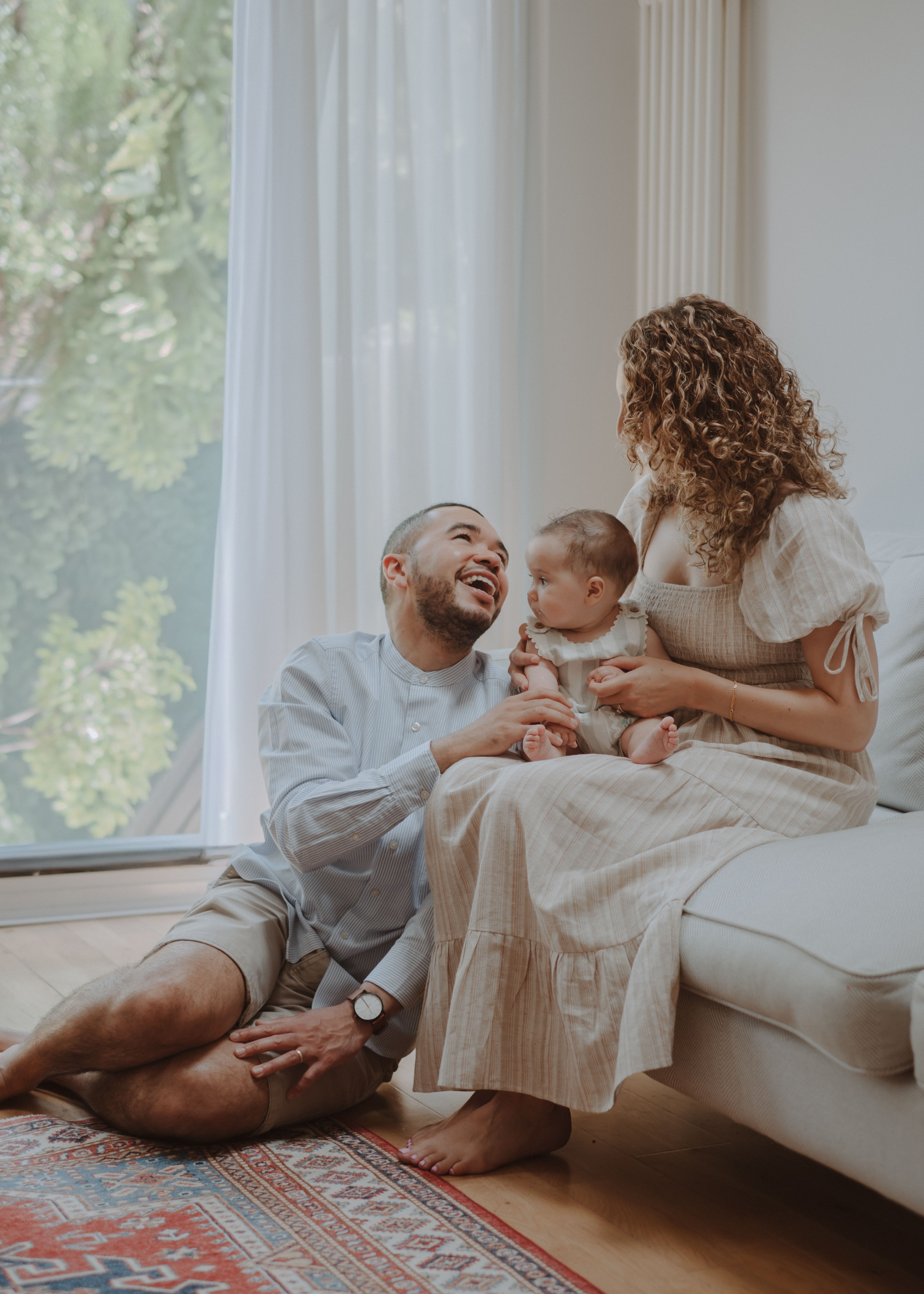 Parent gently holding their newborn baby beside a softly lit window at home