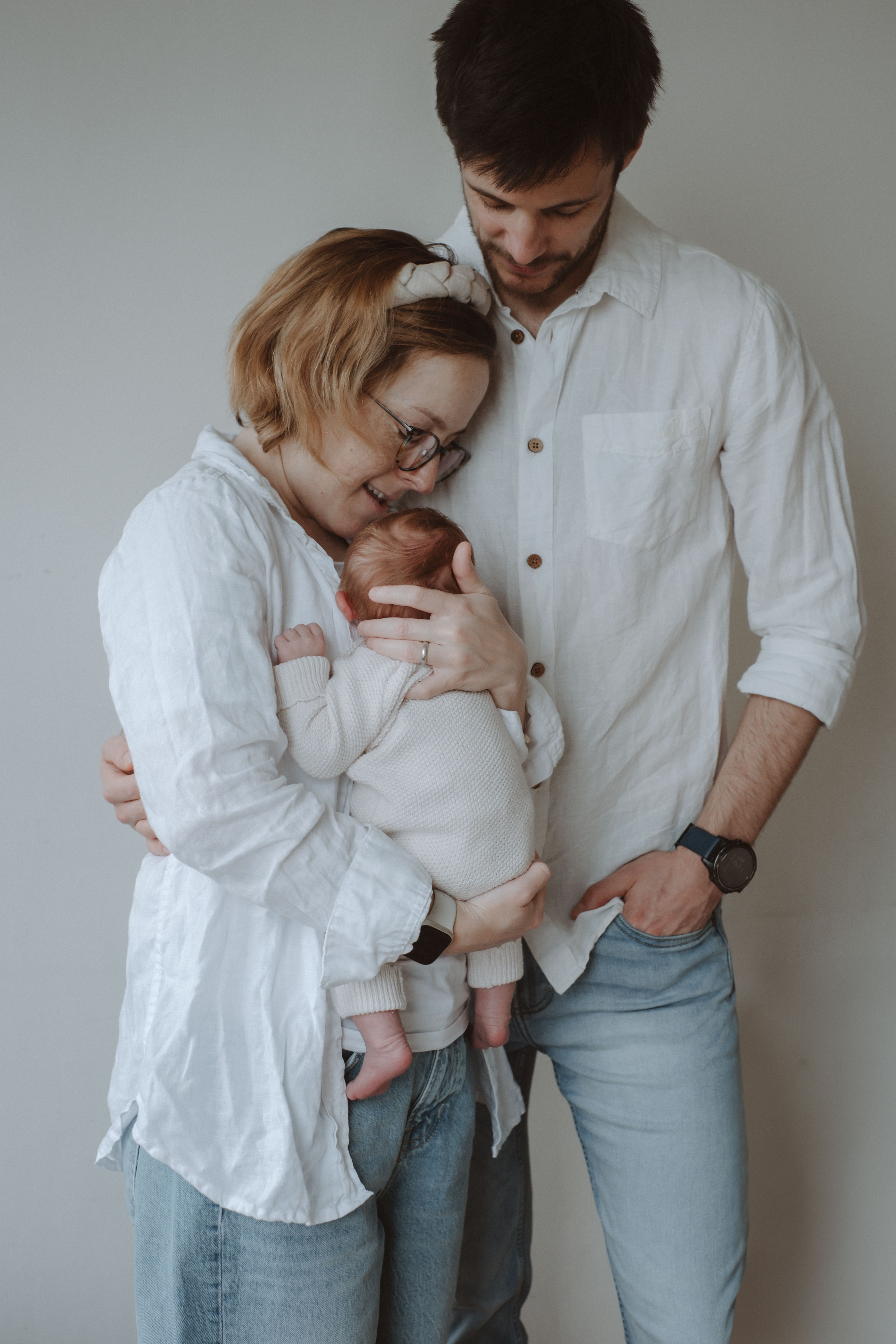 Parent gently holding their newborn baby beside a softly lit window at home