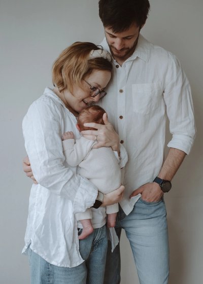 Parent gently holding their newborn baby beside a softly lit window at home