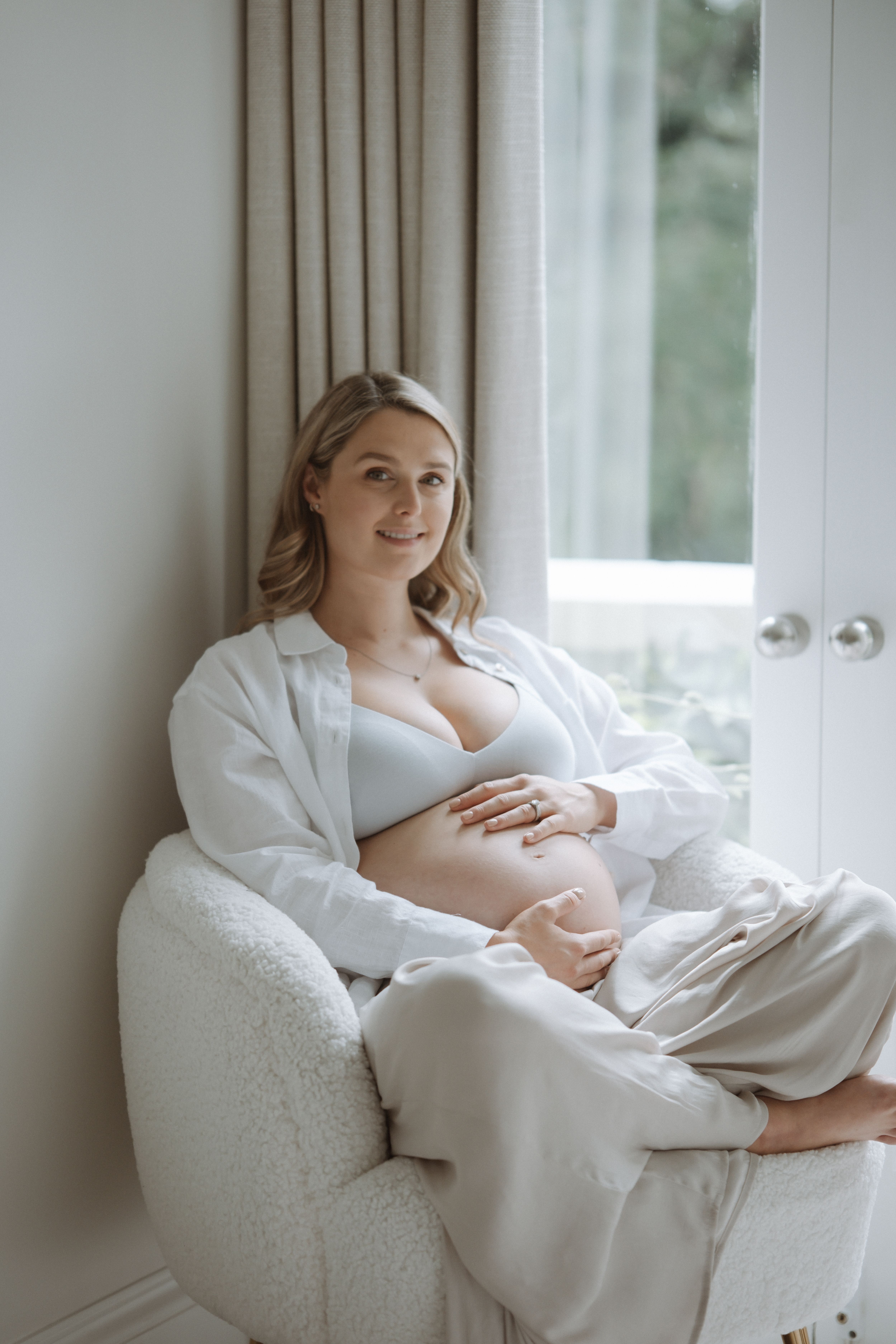 Pregnant mother standing in soft natural light during a relaxed maternity session