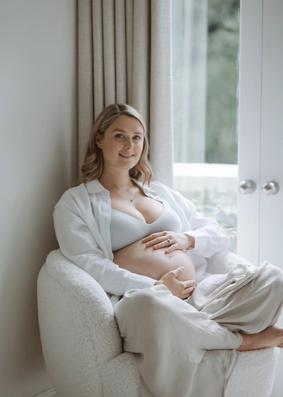 Pregnant mother standing in soft natural light during a relaxed maternity session
