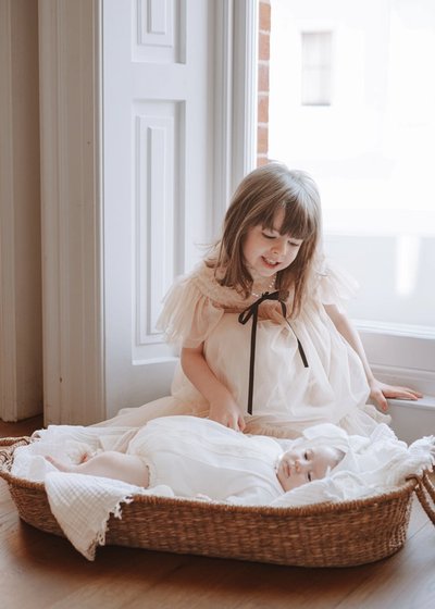 Parent gently holding their newborn baby beside a softly lit window at home