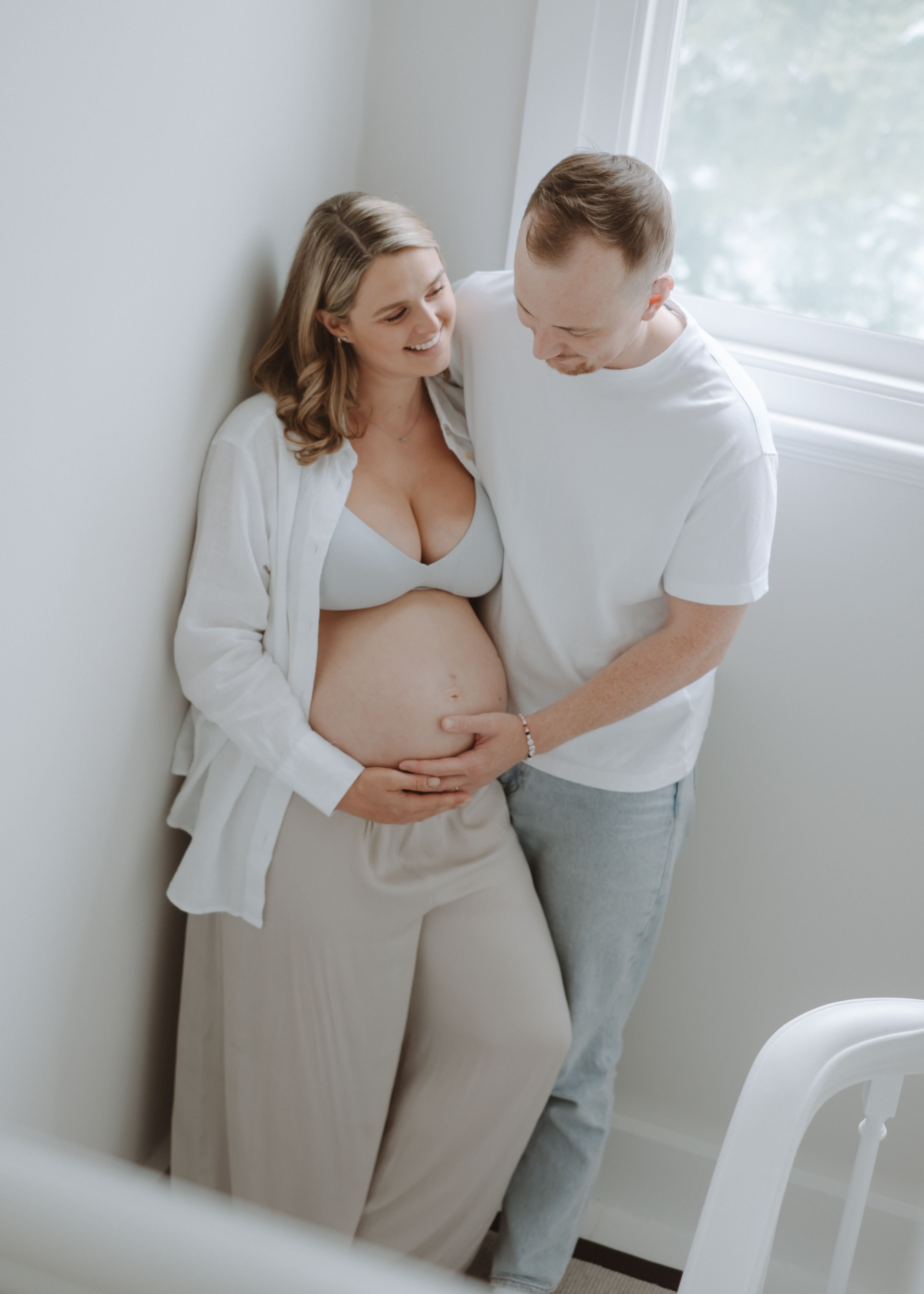 Expectant mother relaxing on a bed during an at-home maternity photography session