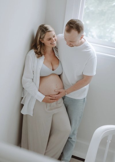 Expectant mother relaxing on a bed during an at-home maternity photography session