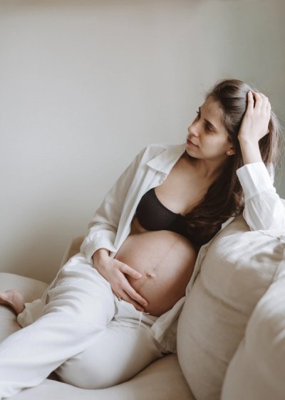 Expectant mother relaxing on a bed during an at-home maternity photography session