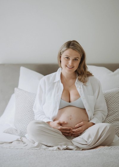 Pregnant mother seated at home with her hands resting gently on her bump
