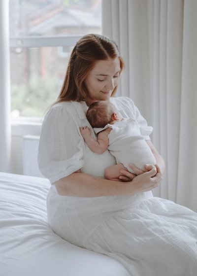 Newborn baby photographed with an older sibling in a bright family home