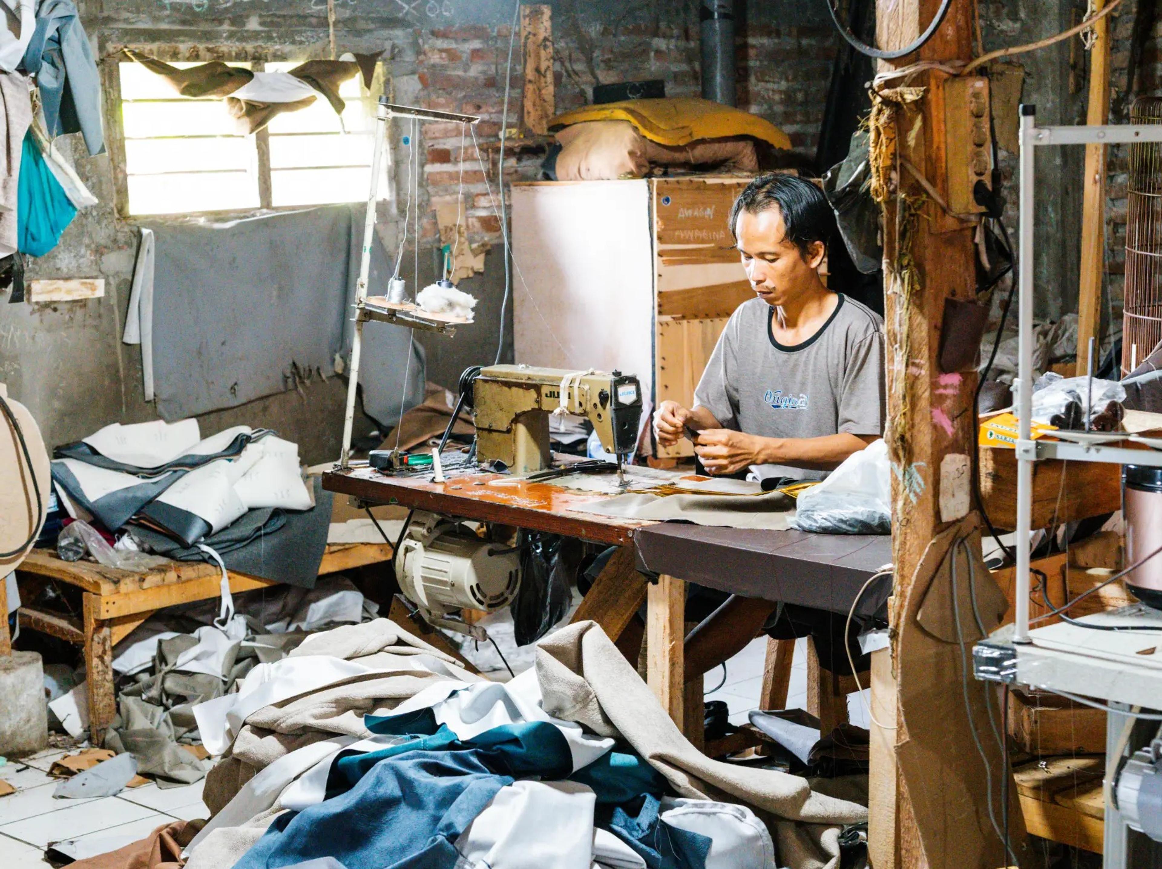 Penjahit menjahit kain sofa dengan mesin jahit di workshop Emerald