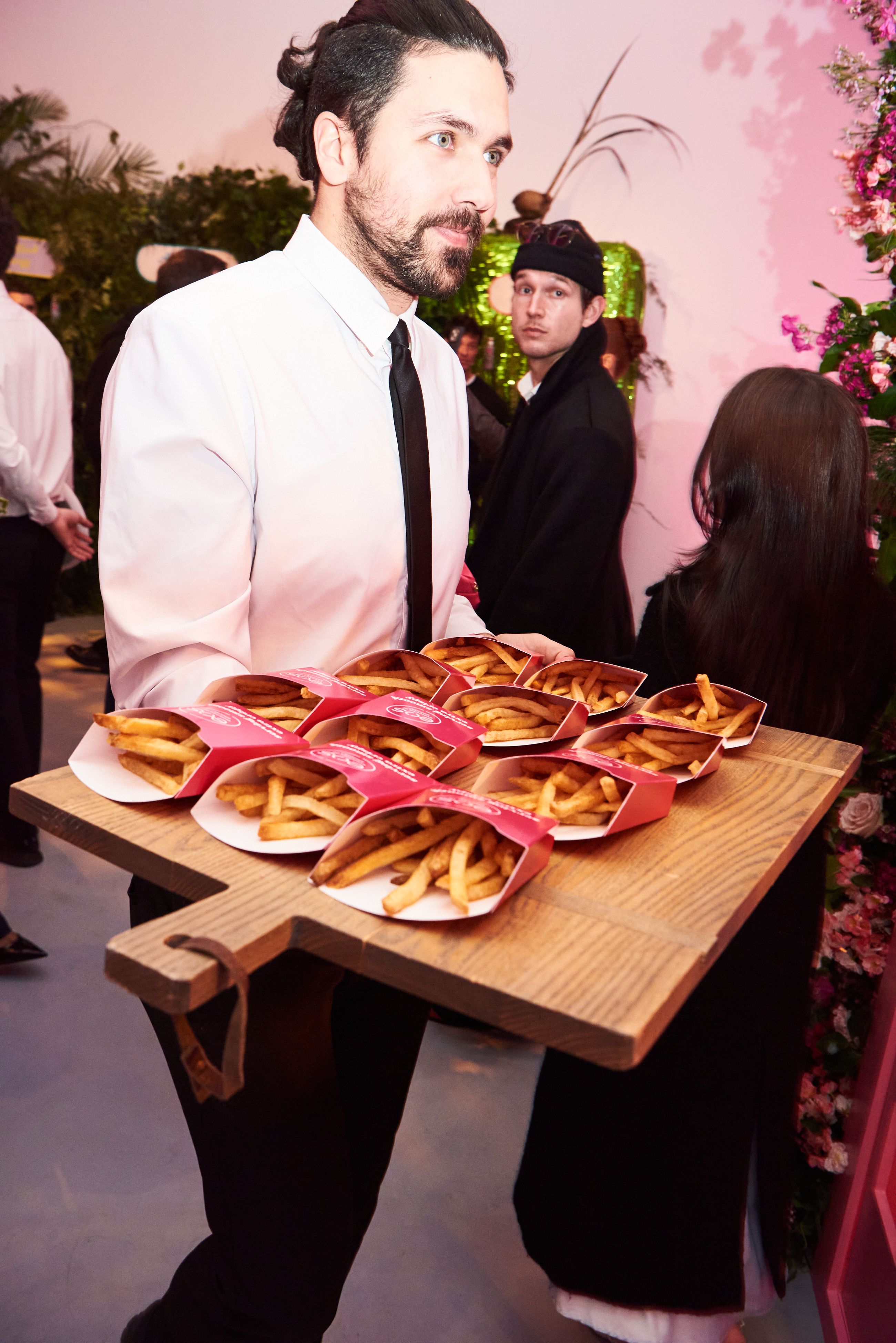 Server presenting trays of fries as passed appetizers during a brand activation event.