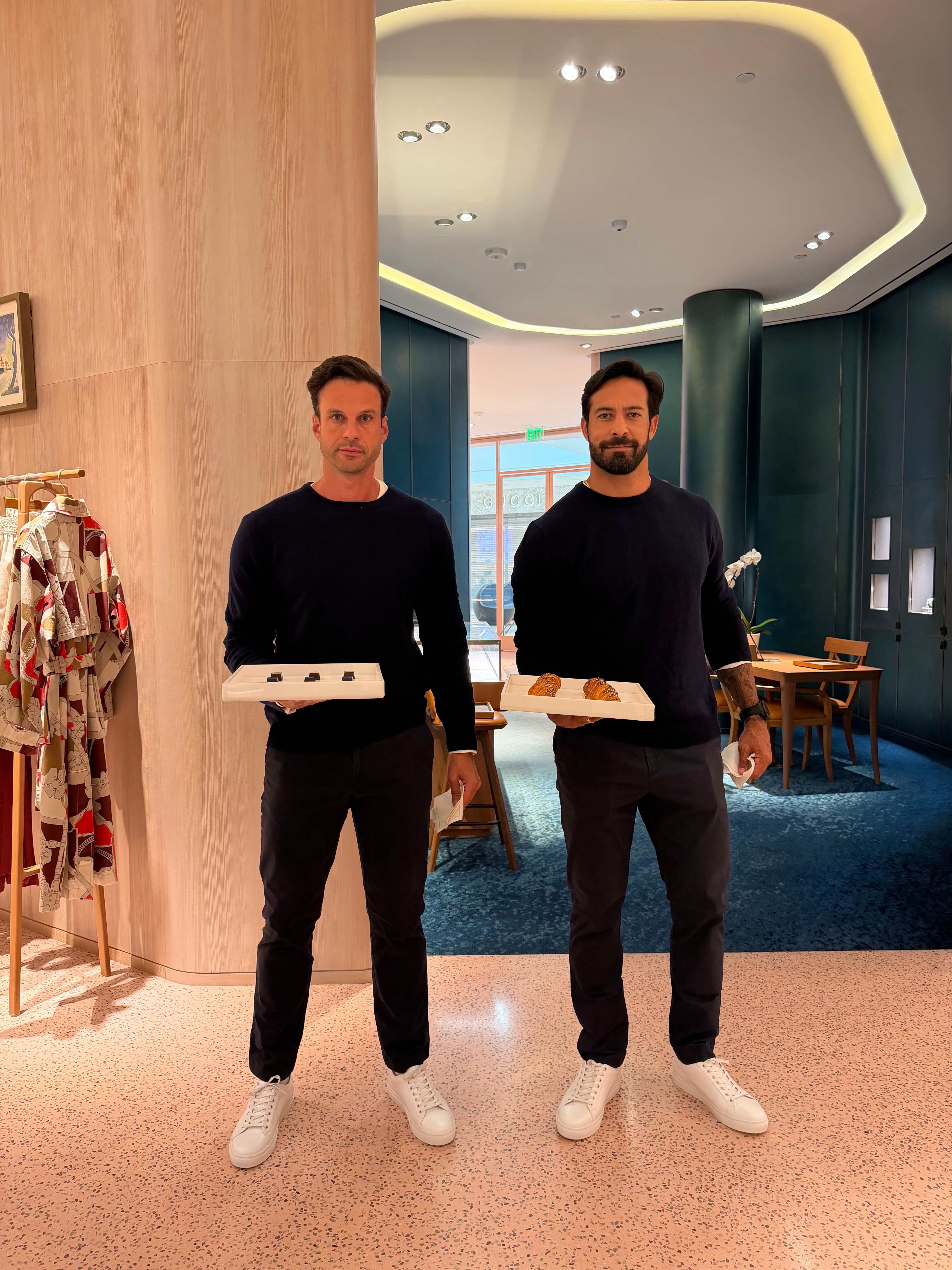 Miami servers in dark-blue uniforms holding trays of pastries and chocolates in Hermes flagship in Miami.