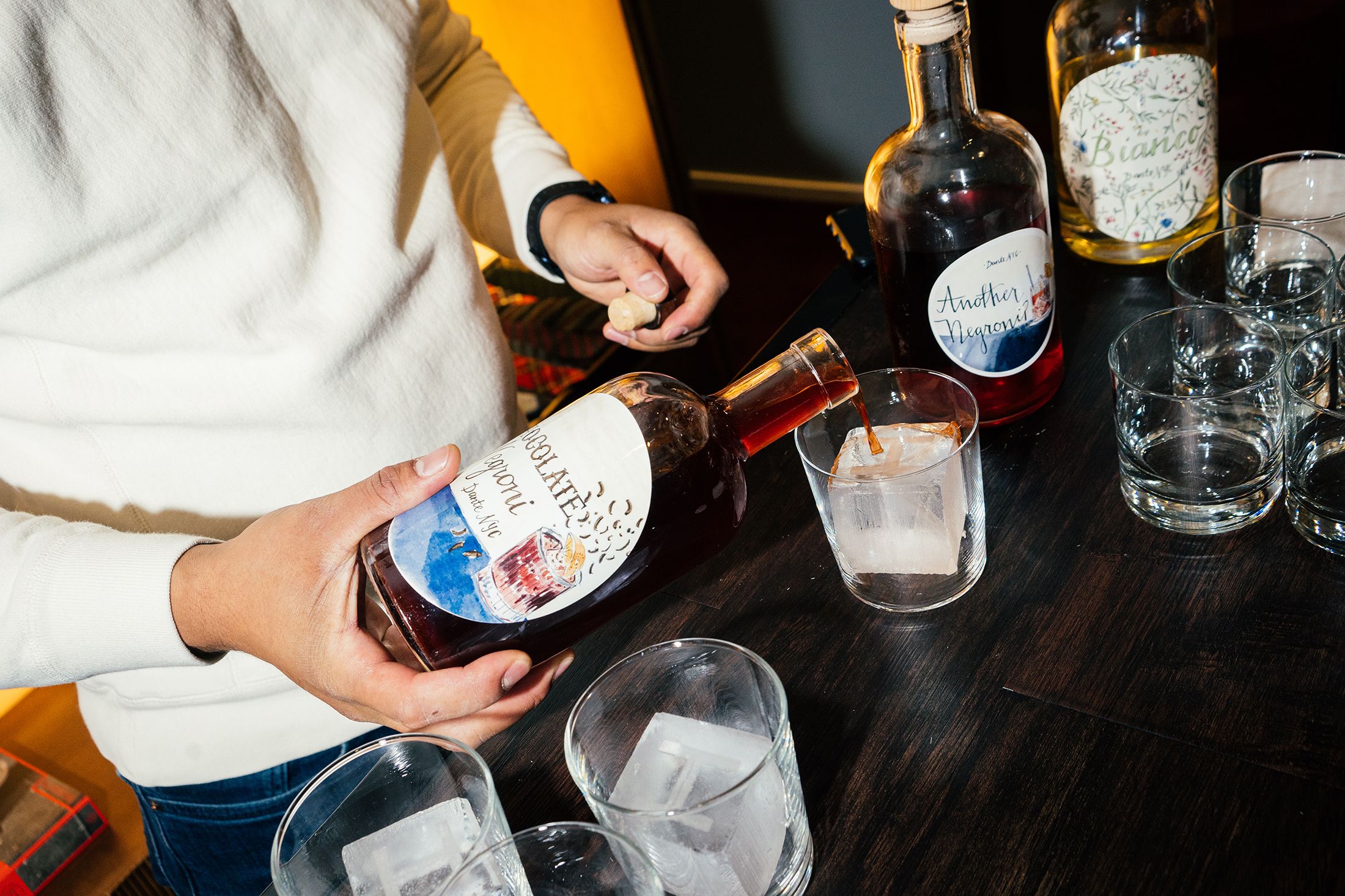 Bartender pouring a cocktail over ice at an event catering bar station.