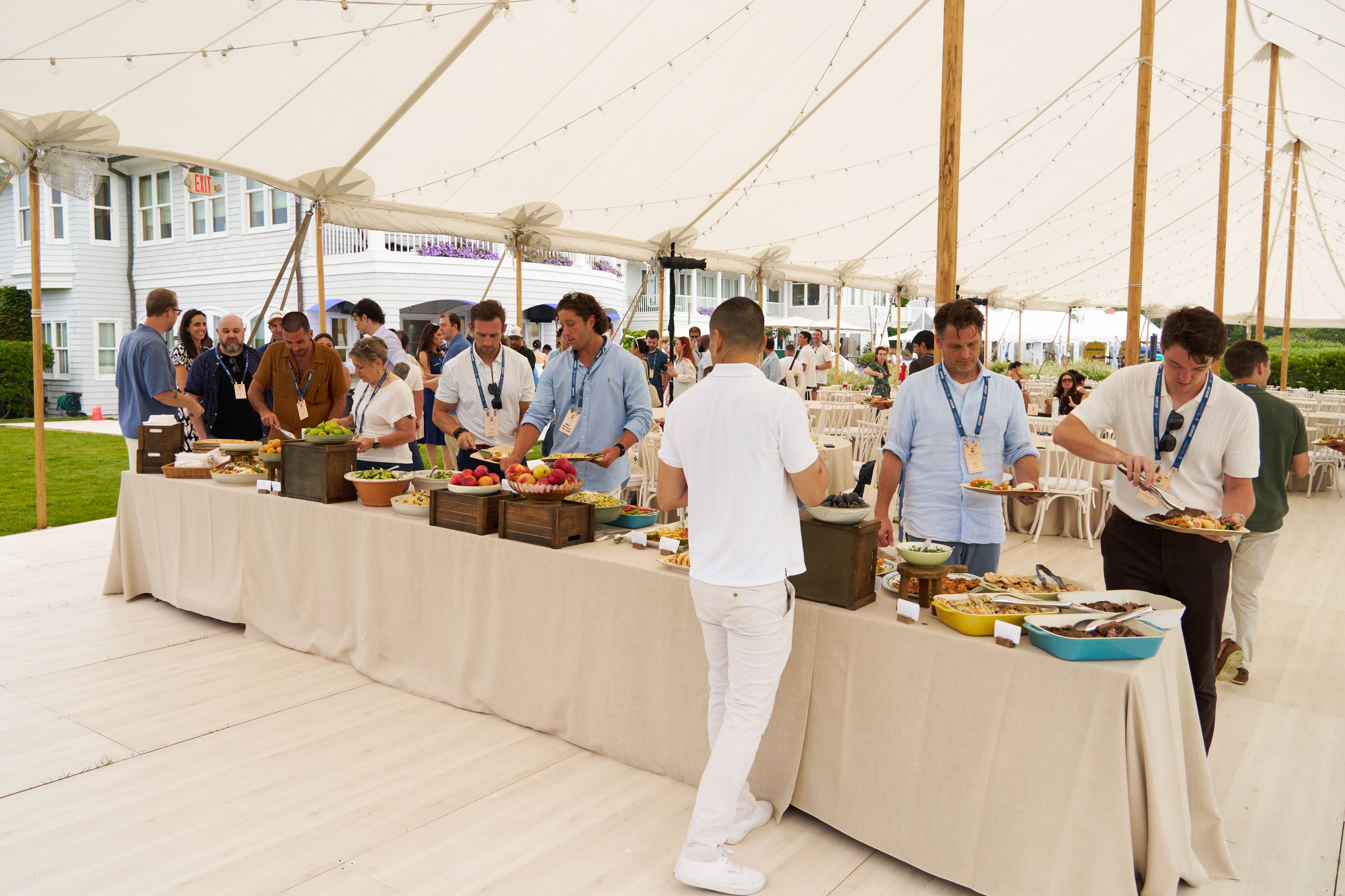 Attendees serving themselves from a buffet under a large white tent.