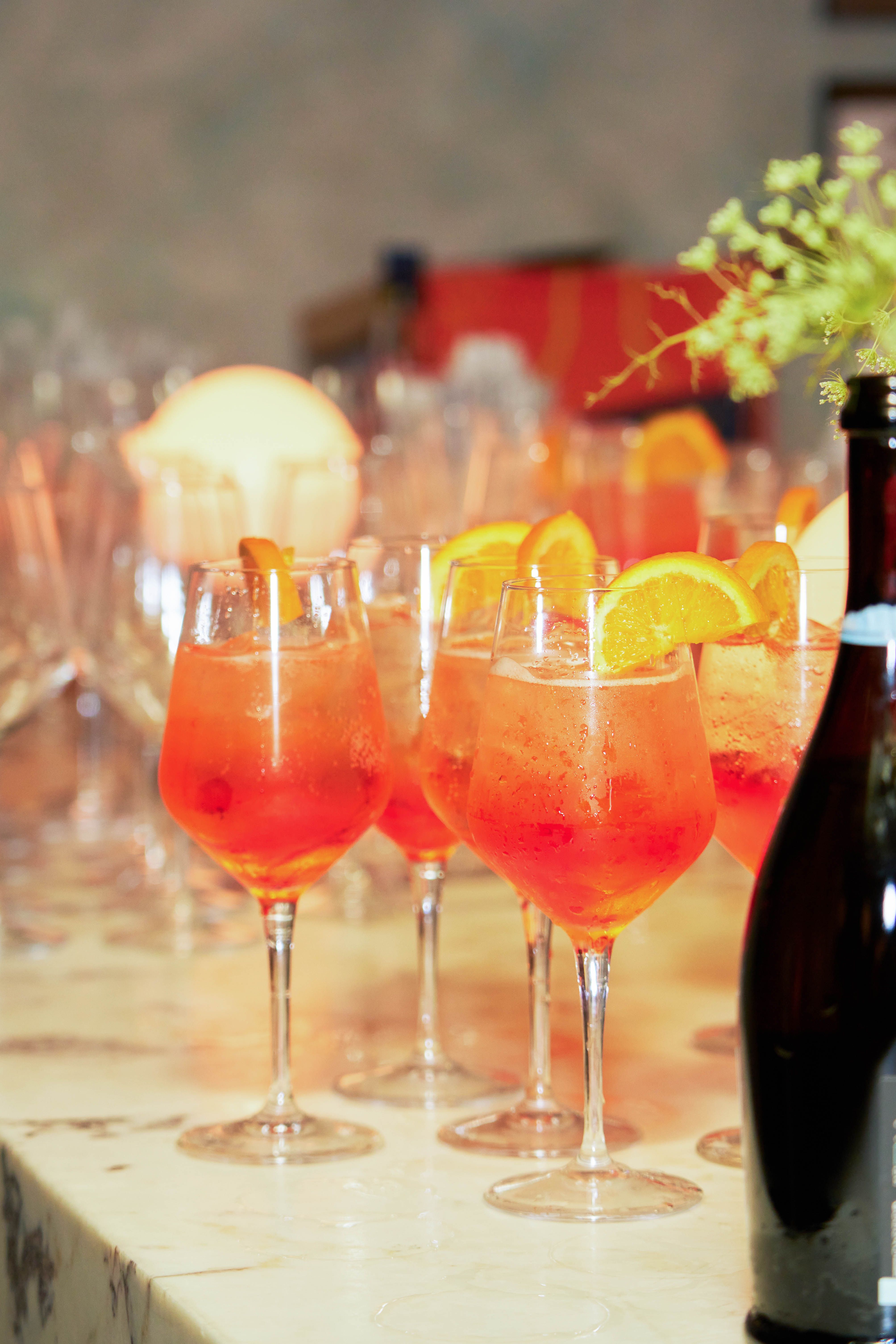 Aperol spritz cocktails with orange slices served in wine glasses at an event bar catering.