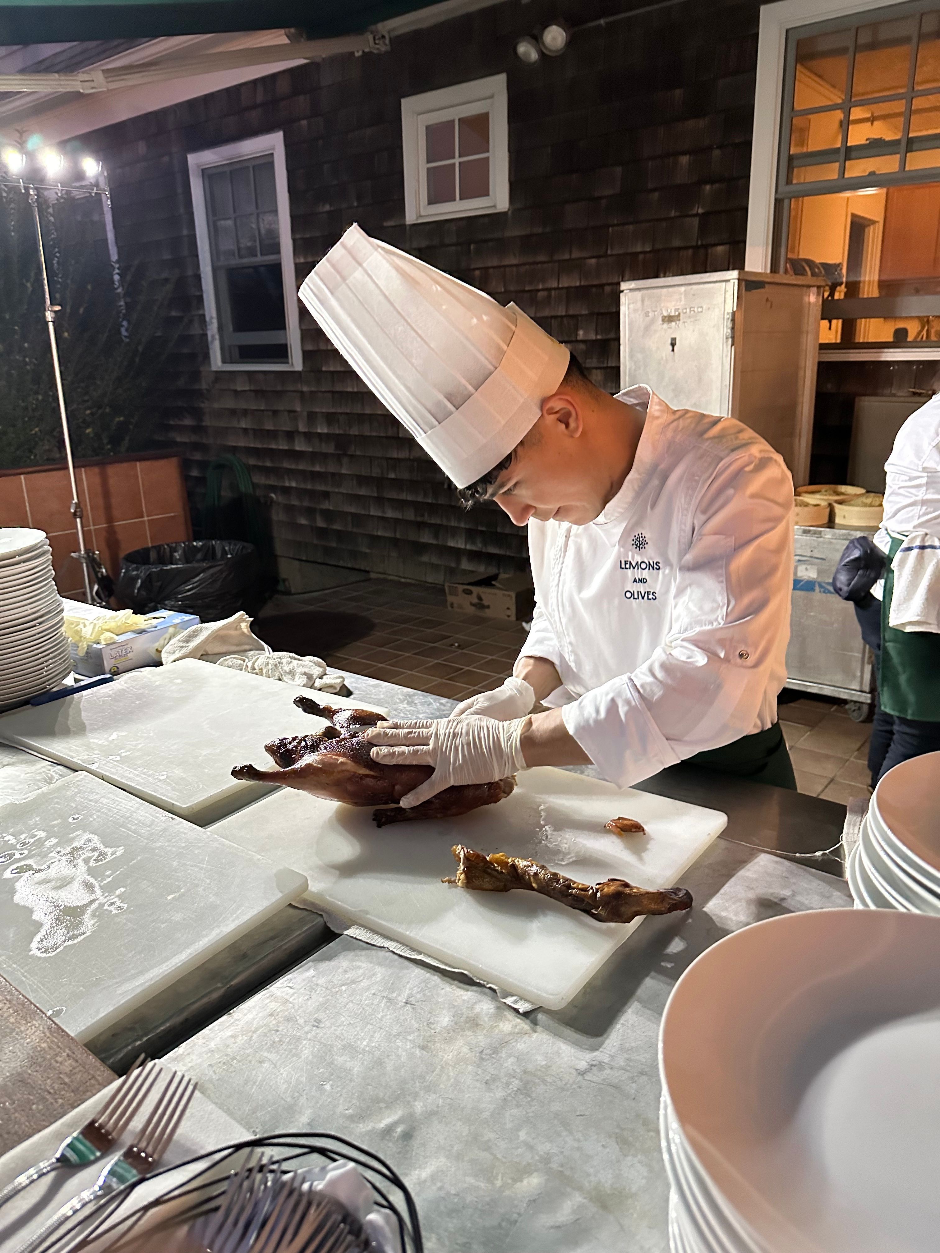 Chef preparing roasted duck at live carving station during private catering event