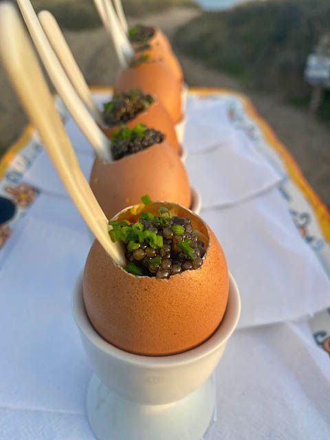 Elegant egg shell canapé filled with caviar and herbs served as a luxury event appetizer.