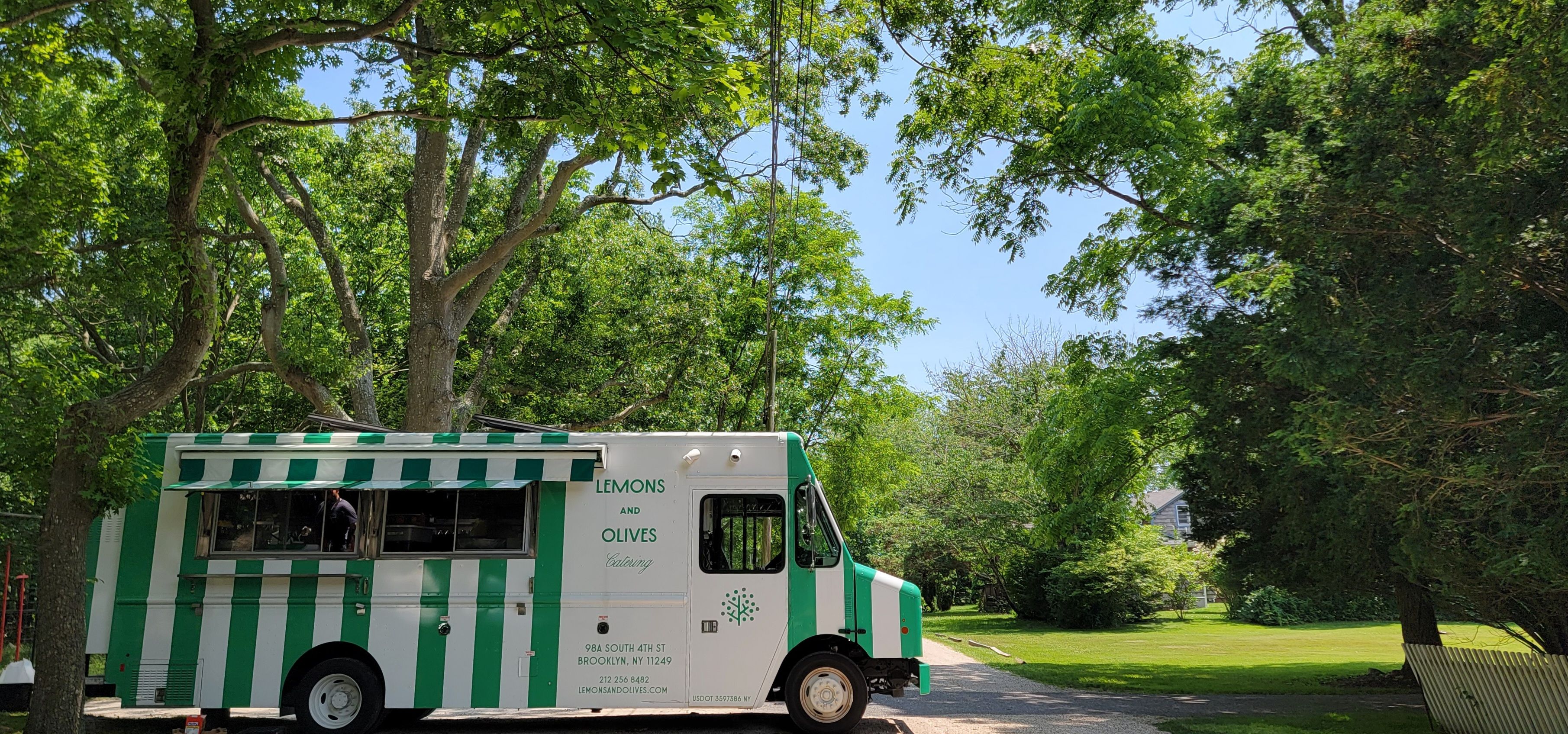 Lemons and Olives mobile catering truck parked at an outdoor event venue surrounded by trees.