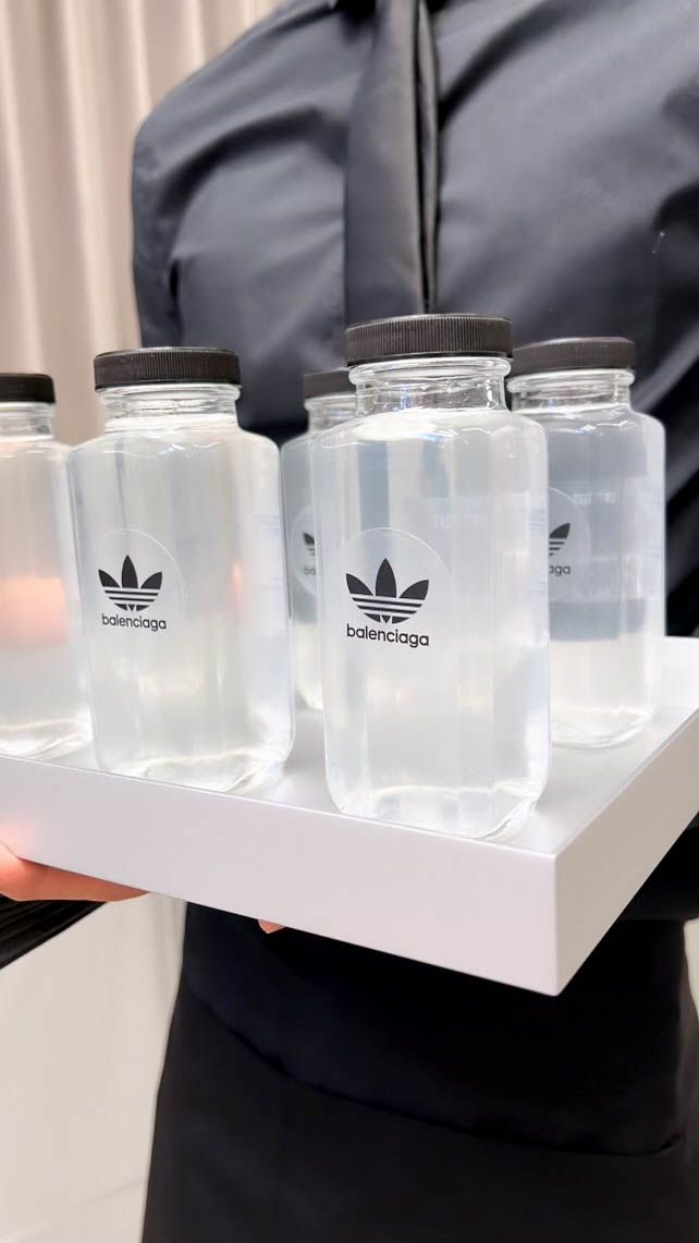 Branded Balenciaga beverages served on a tray by event staff during a fashion brand activation.