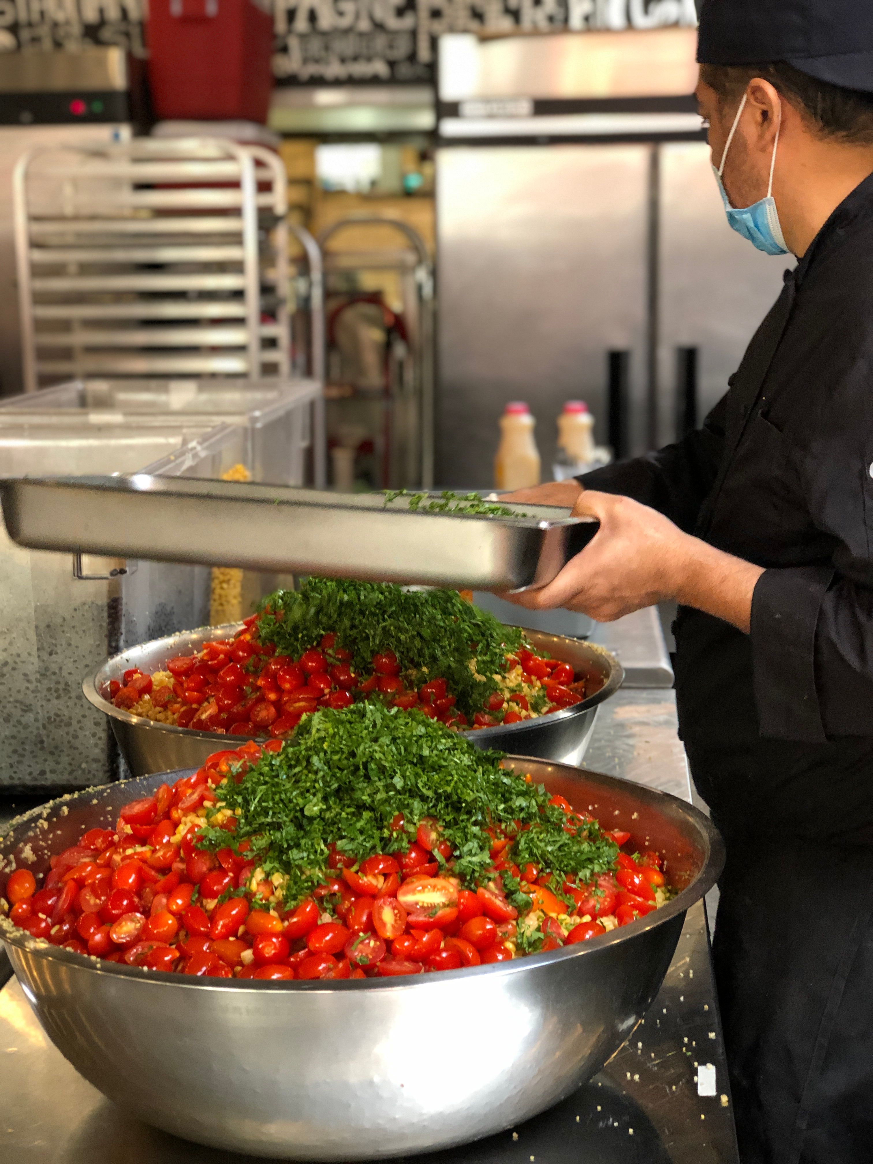 Large-scale food preparation for emergency catering with fresh ingredients being assembled in a professional kitchen.