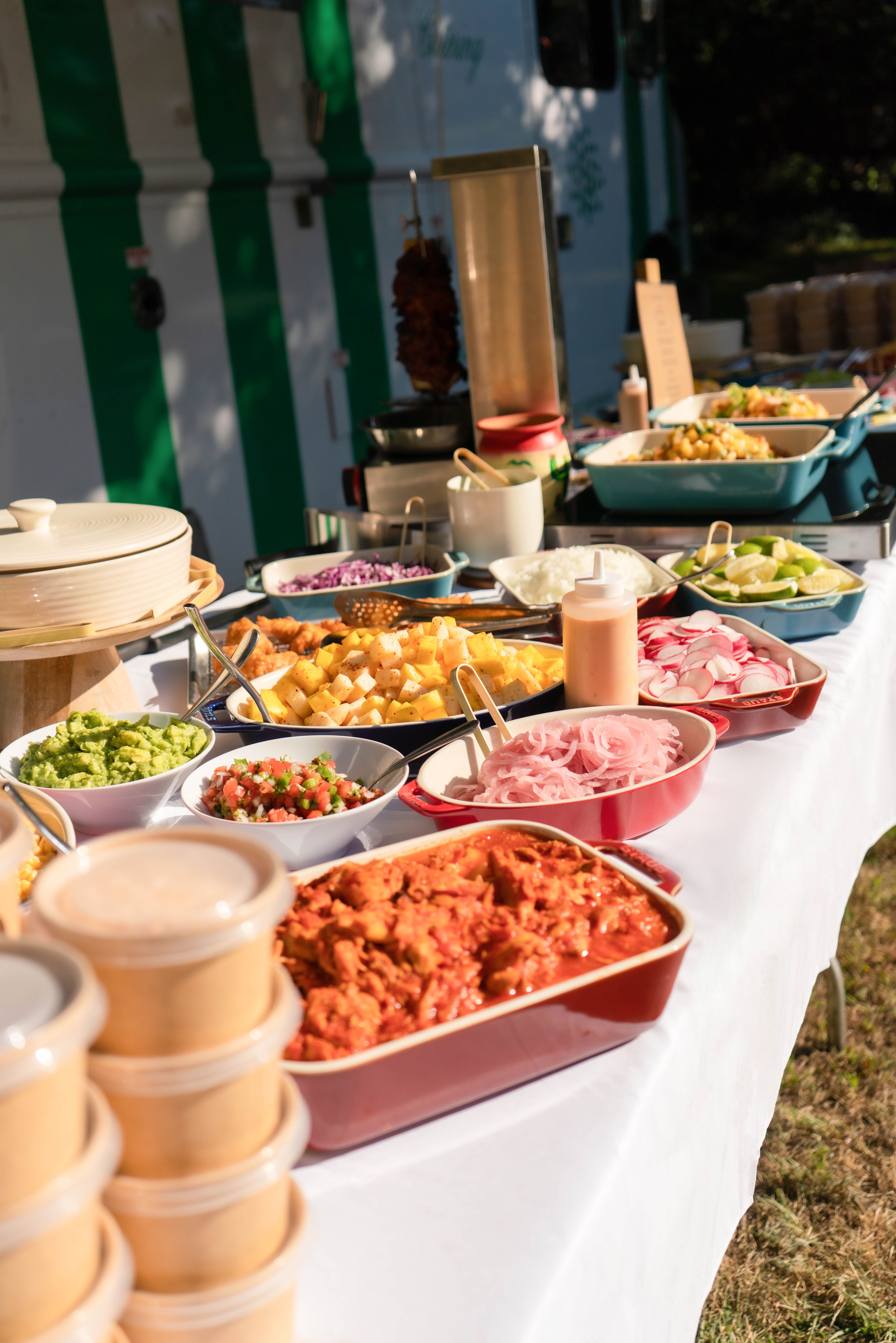 Wedding catering buffet with fresh toppings, vegetables, and sauces served outdoors at a reception.