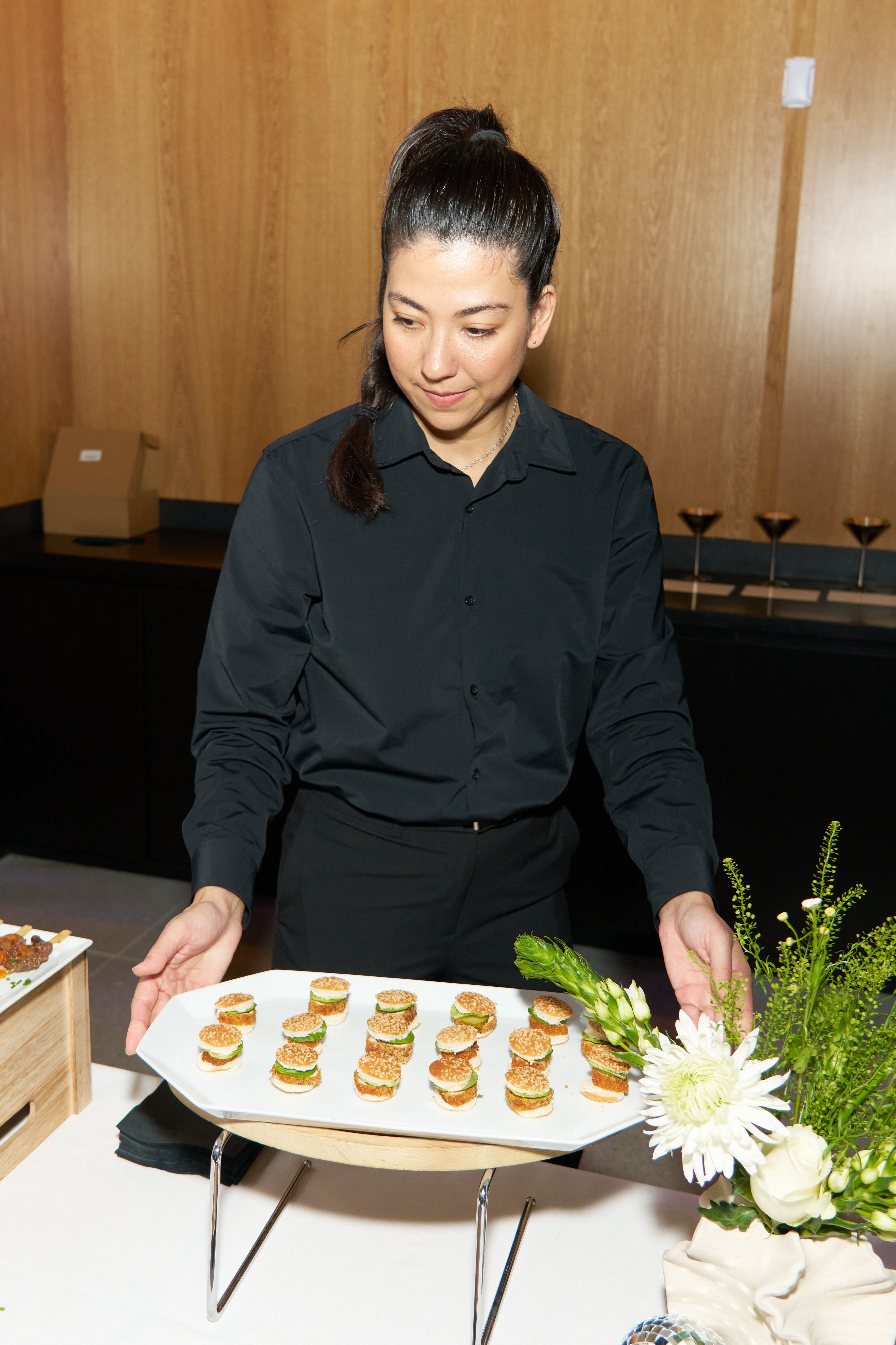 Catering female server presenting tray of mini slider hors d'oeuvres at an event reception.