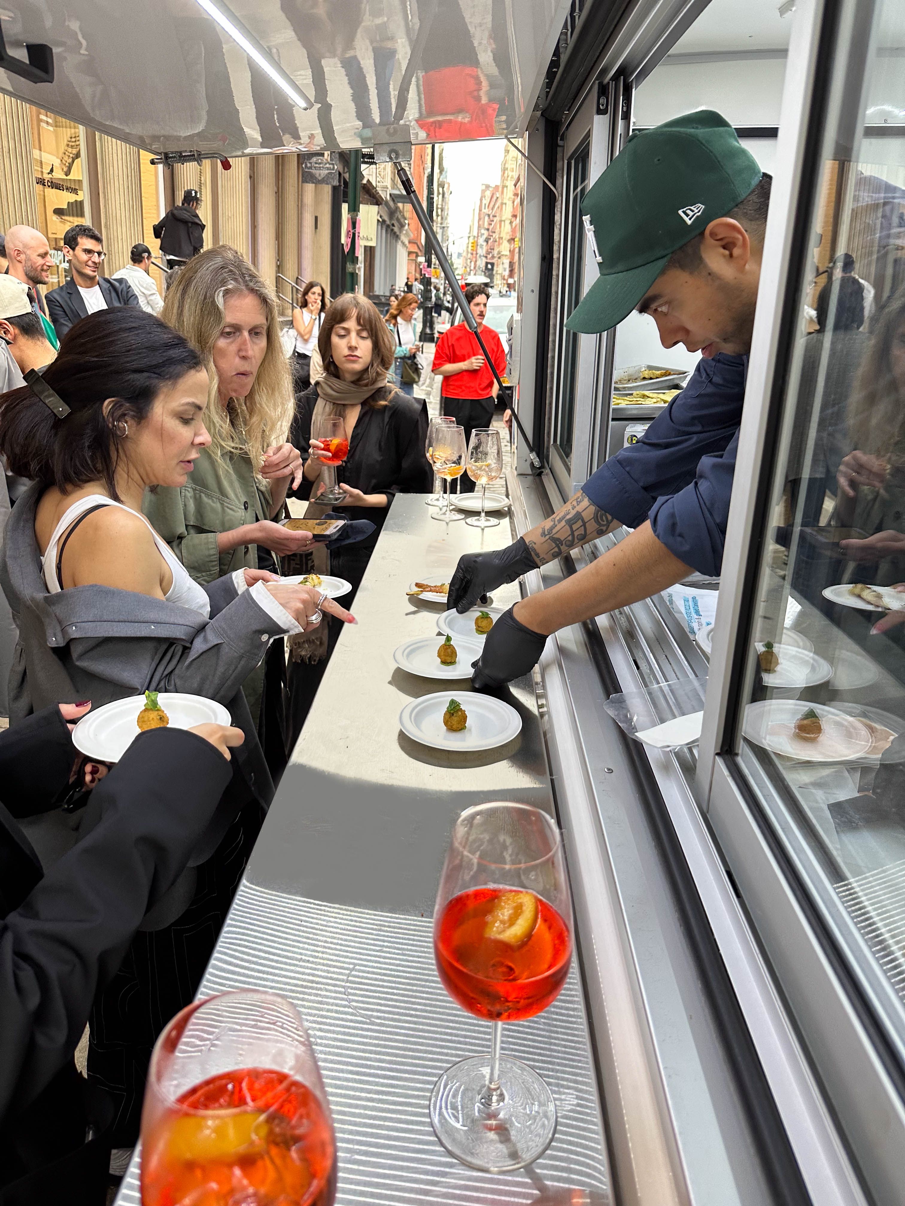Chef serving appetizer bites from a catering food truck during a brand activation event.