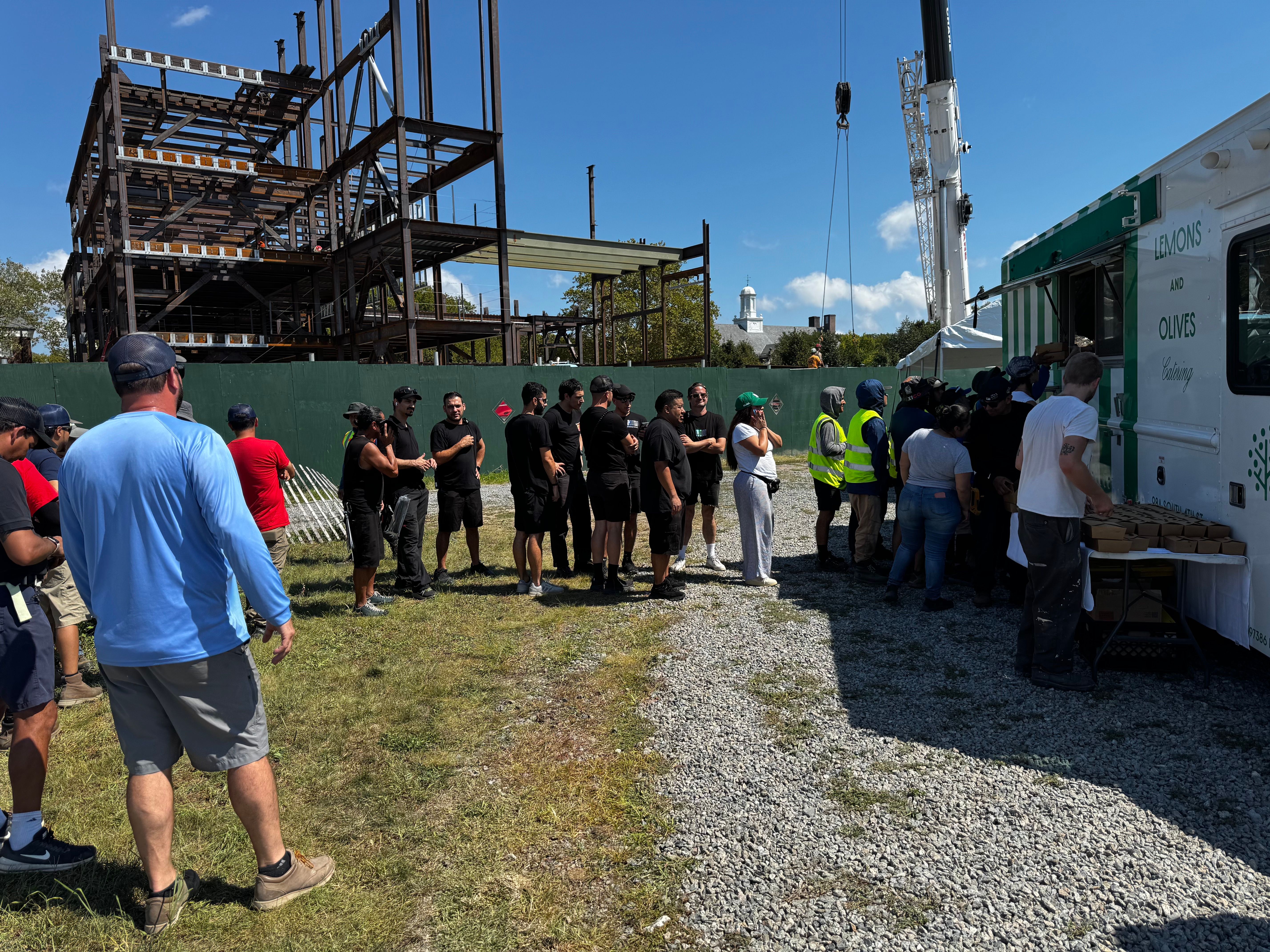 People lining up in front of a mobile kitchen catered event.