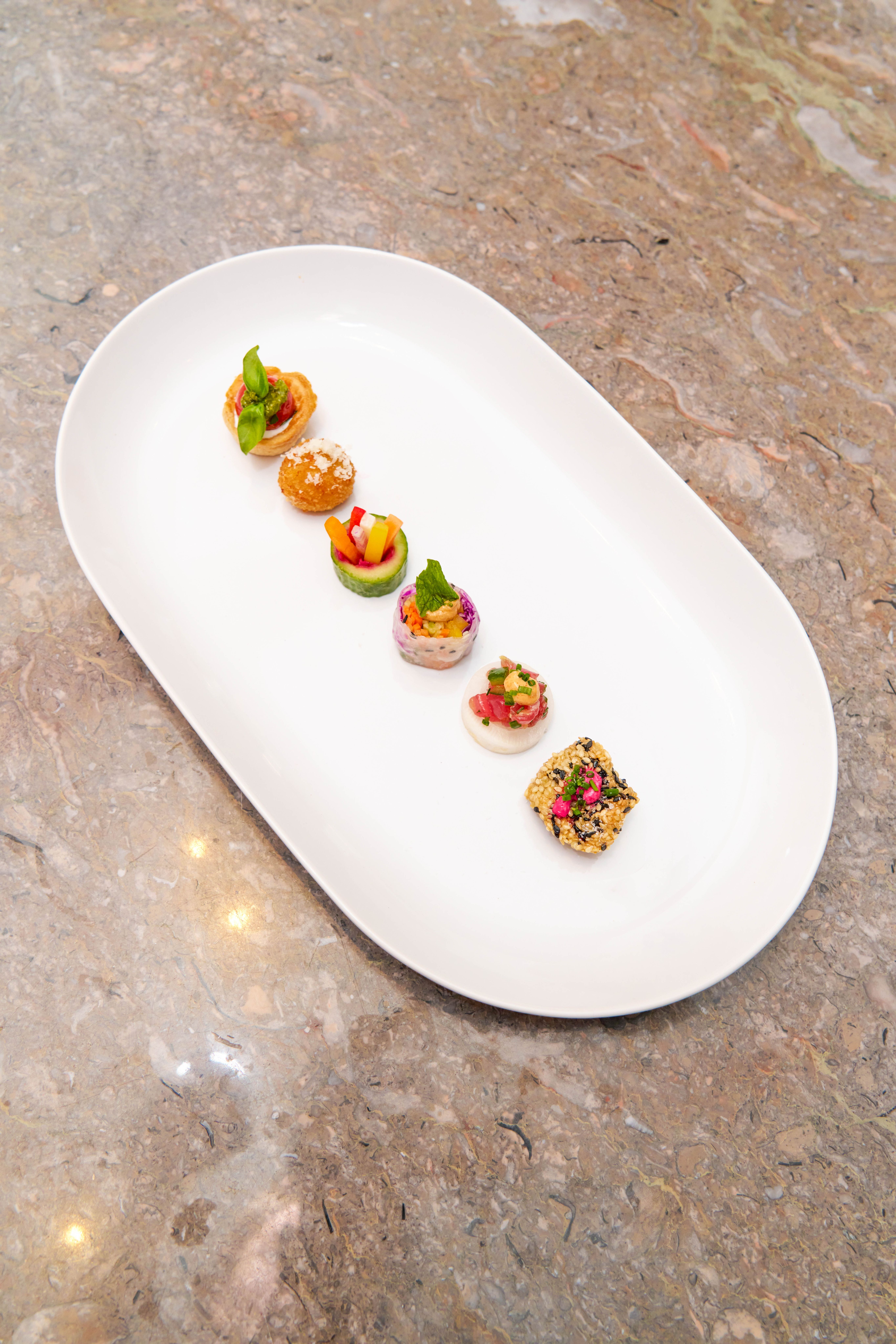 Fine dining catering tasting menu featuring plated appetizer bites arranged on a white dish.