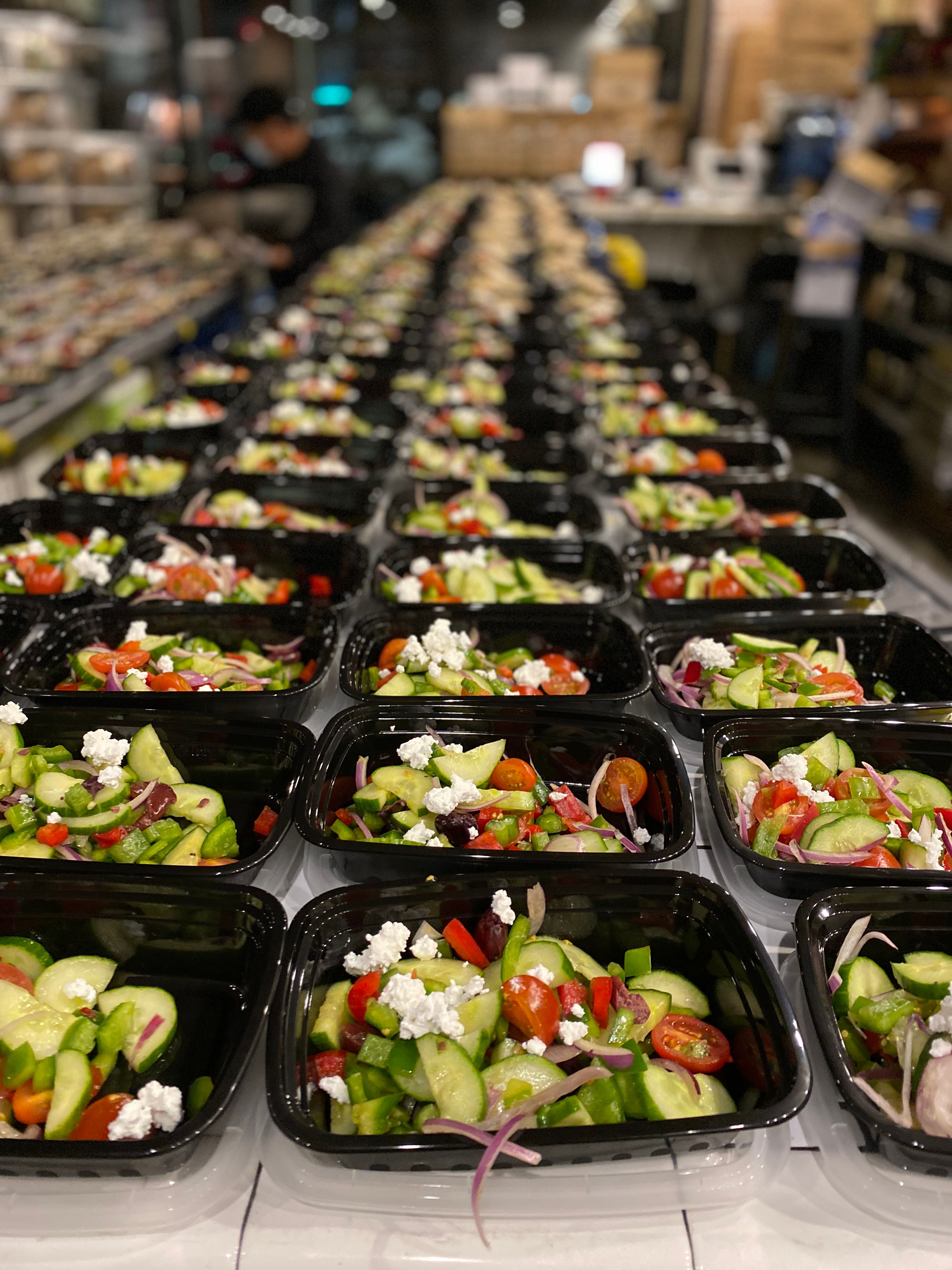 Rows of fresh salad meals being prepared for large-scale emergency meal distribution.